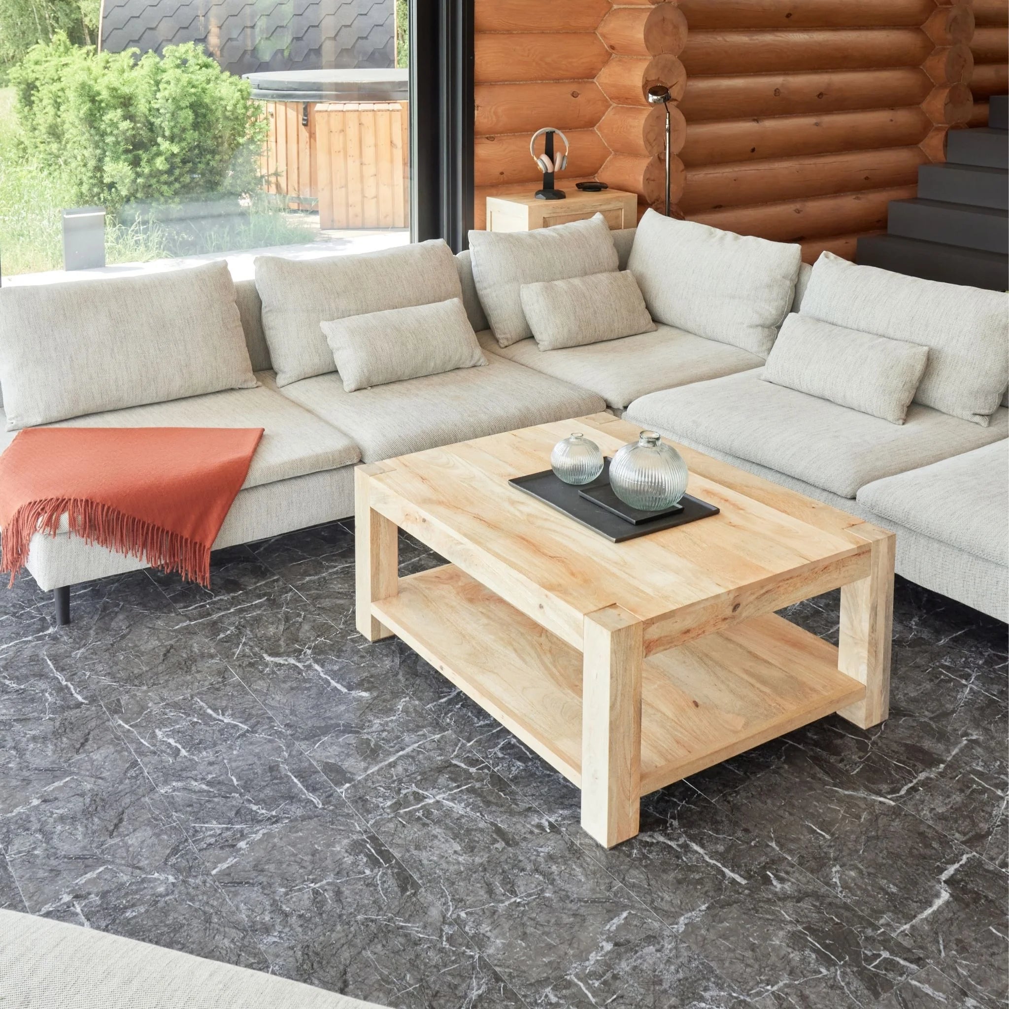 contemporary living room with large beige sofa, wooden coffee table, and black tile flooring