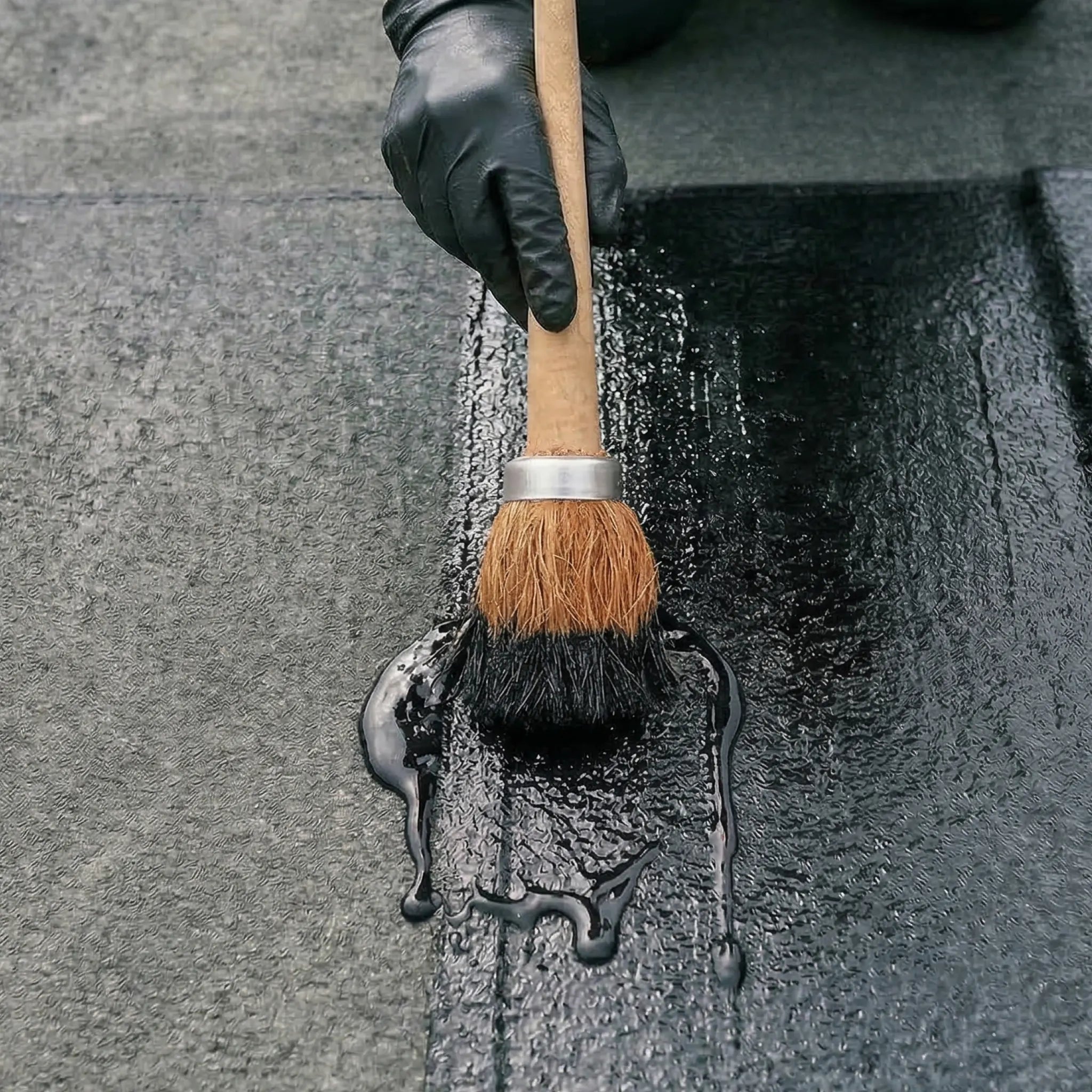 brush applying black adhesive on felt