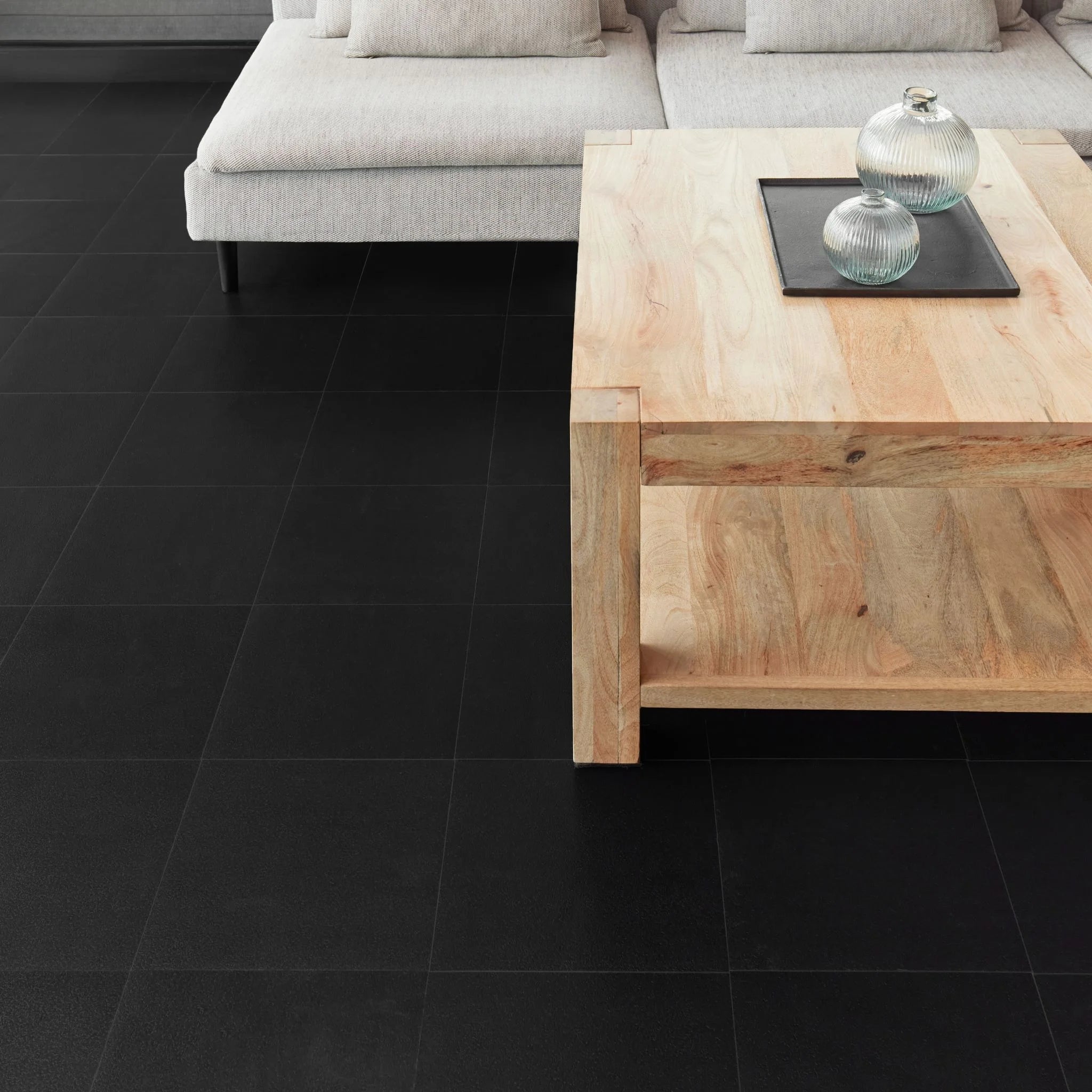 modern living room featuring grey sofa and light wood furniture on black flooring