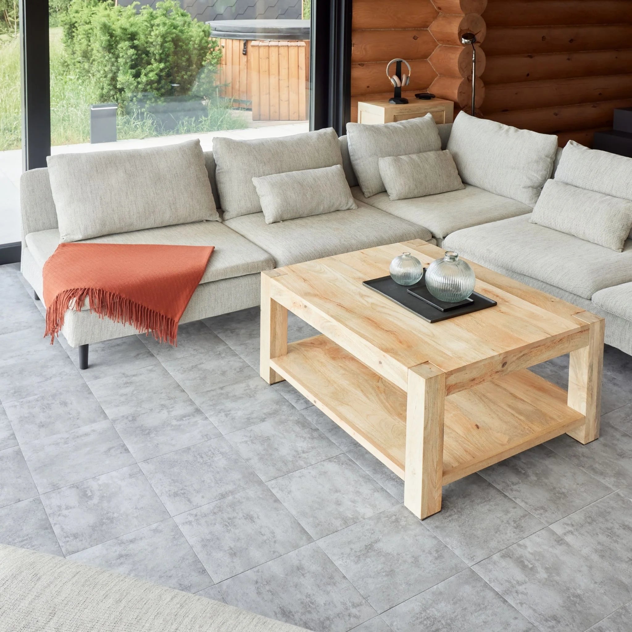 contemporary living room with large beige sofa, wooden coffee table, and grey tile flooring