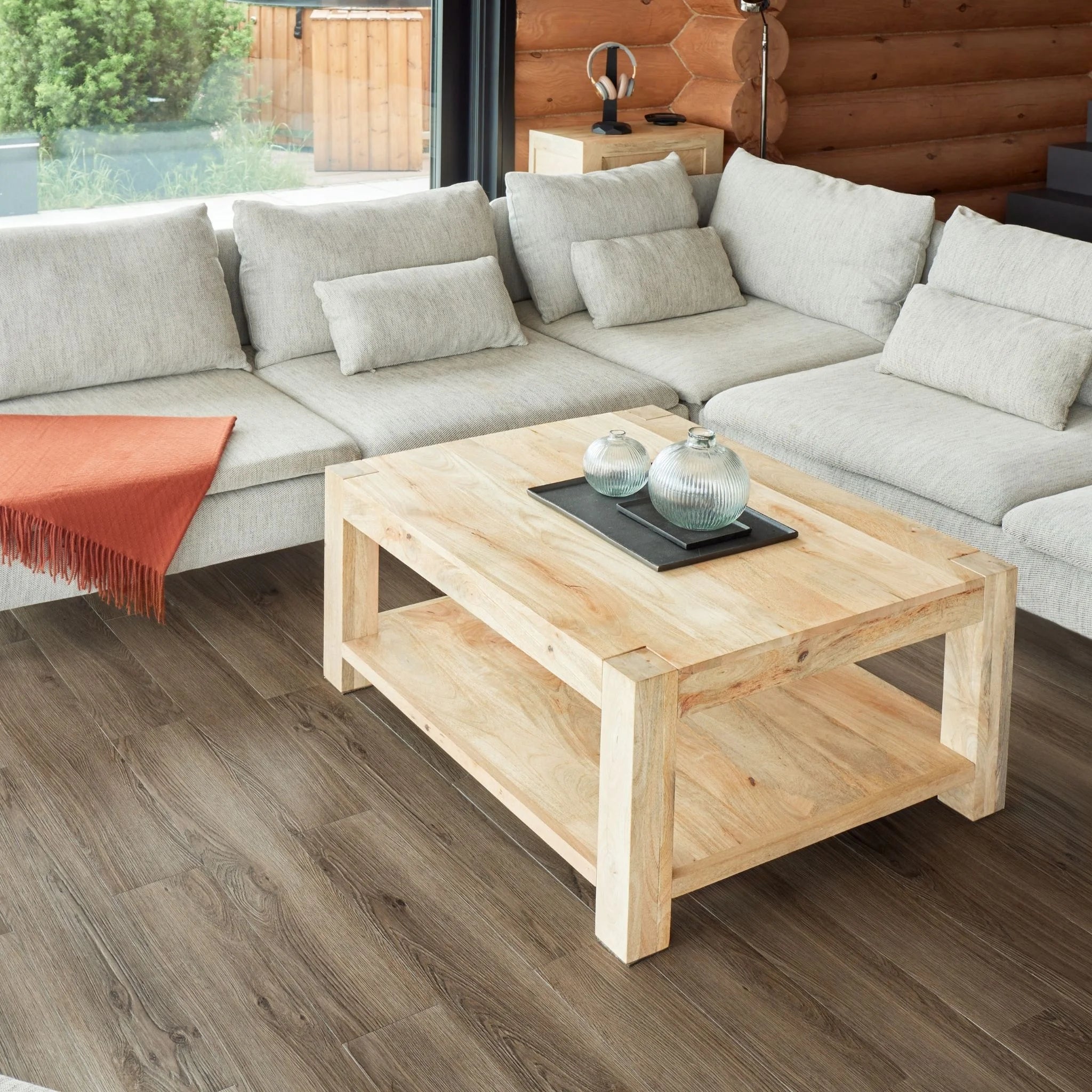 contemporary living room with large beige sofa, wooden coffee table, and dark brown wood flooring