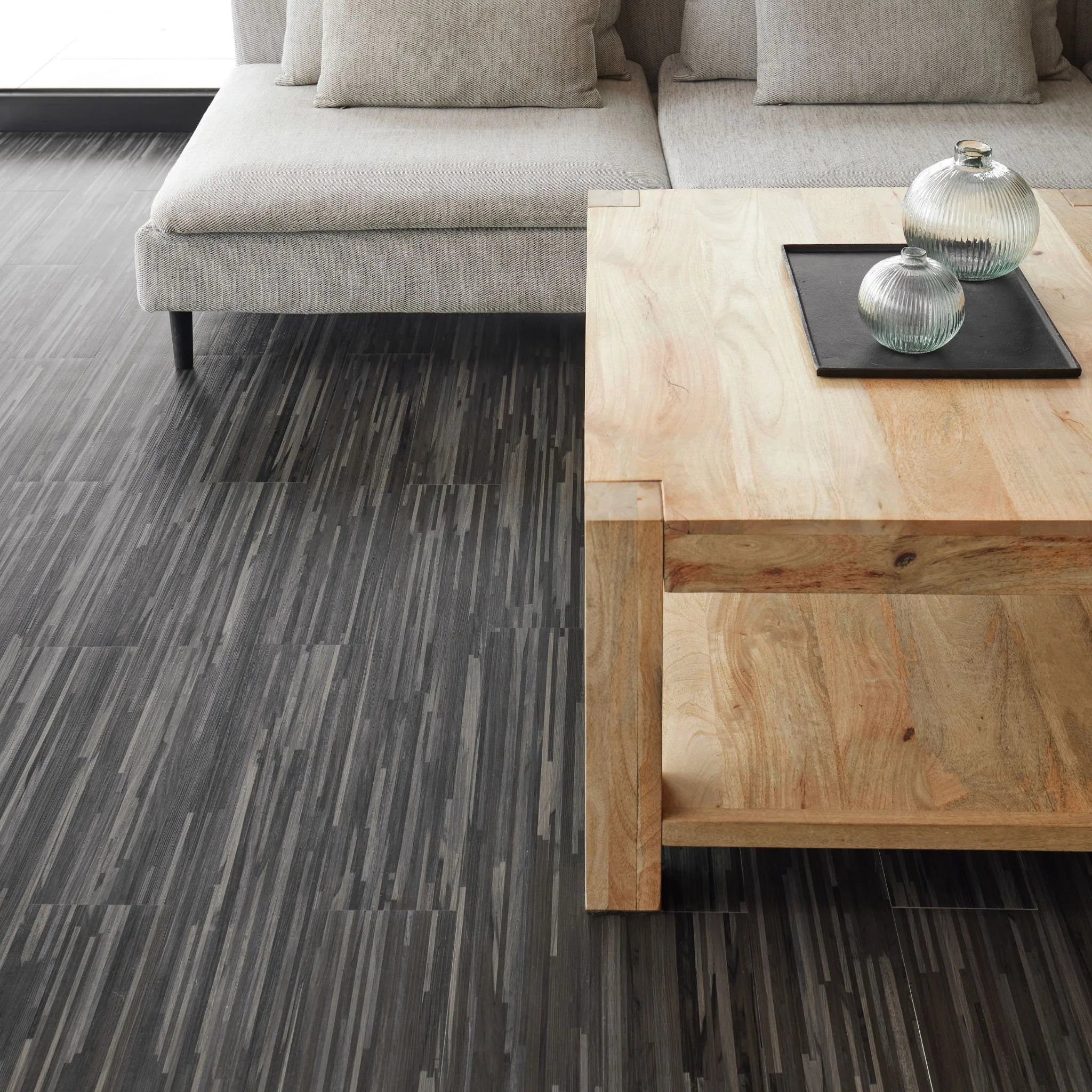 modern living room featuring grey sofa and light wood furniture on dark grey flooring