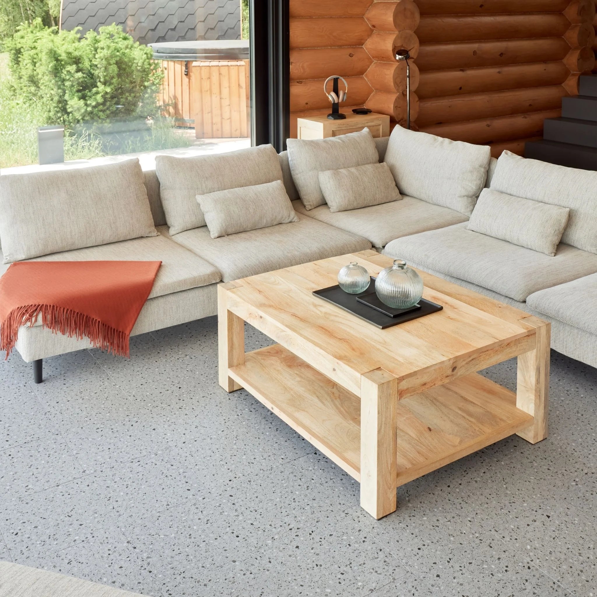contemporary living room with large beige sofa, wooden coffee table, and grey tile flooring