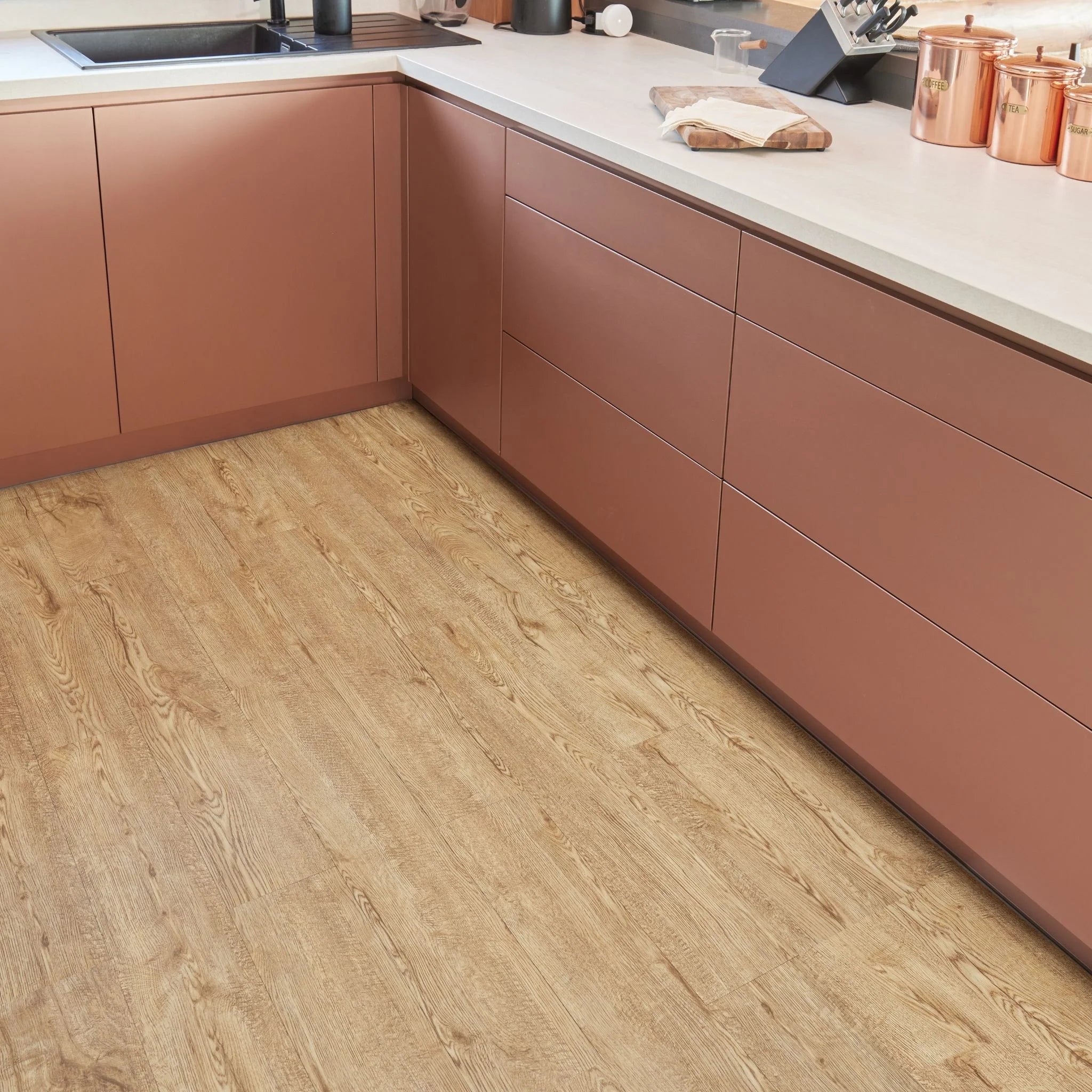 dark beige wooden flooring in a kitchen with brown cabinets