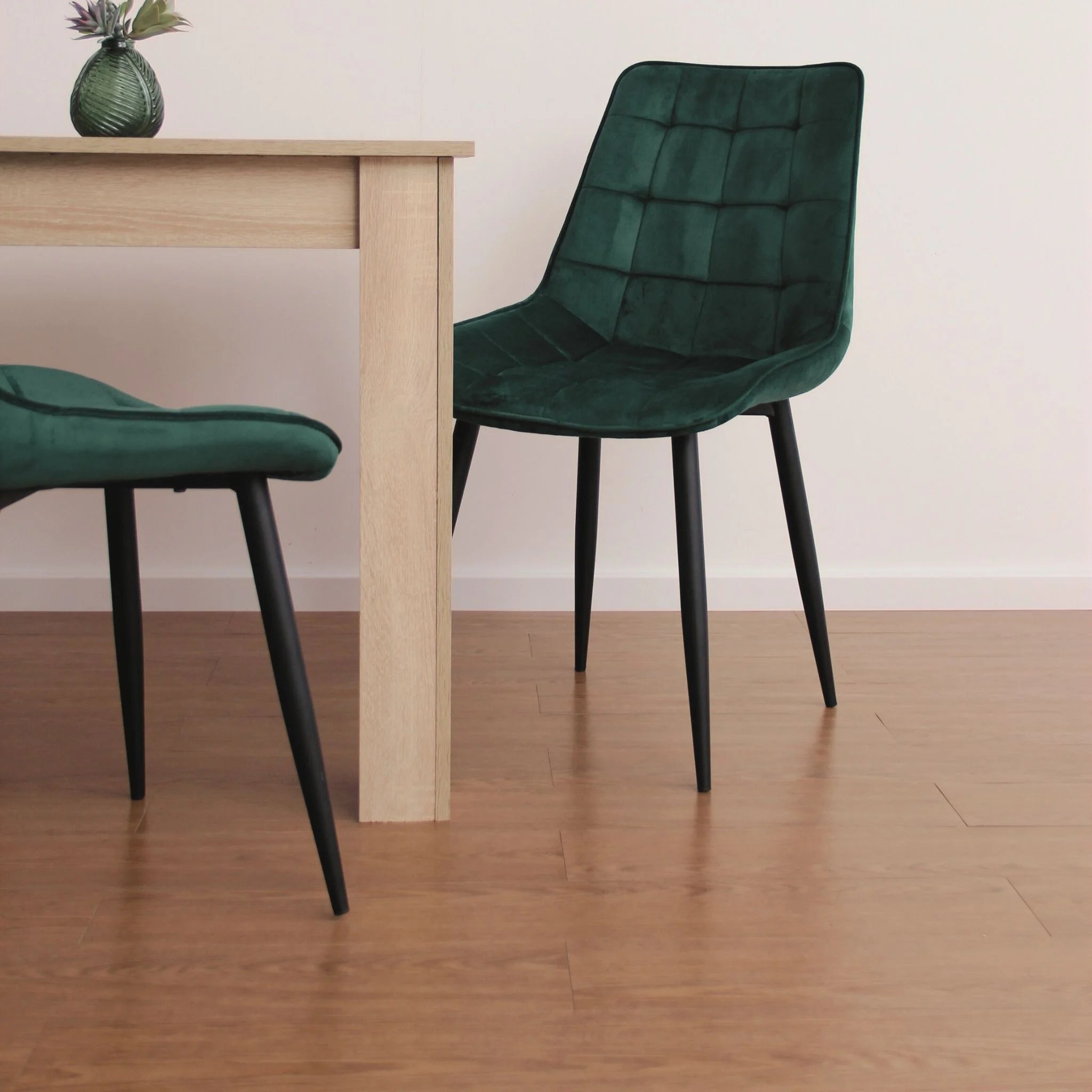 contemporary dining room featuring green velvet chairs and light wood furniture on brown flooring