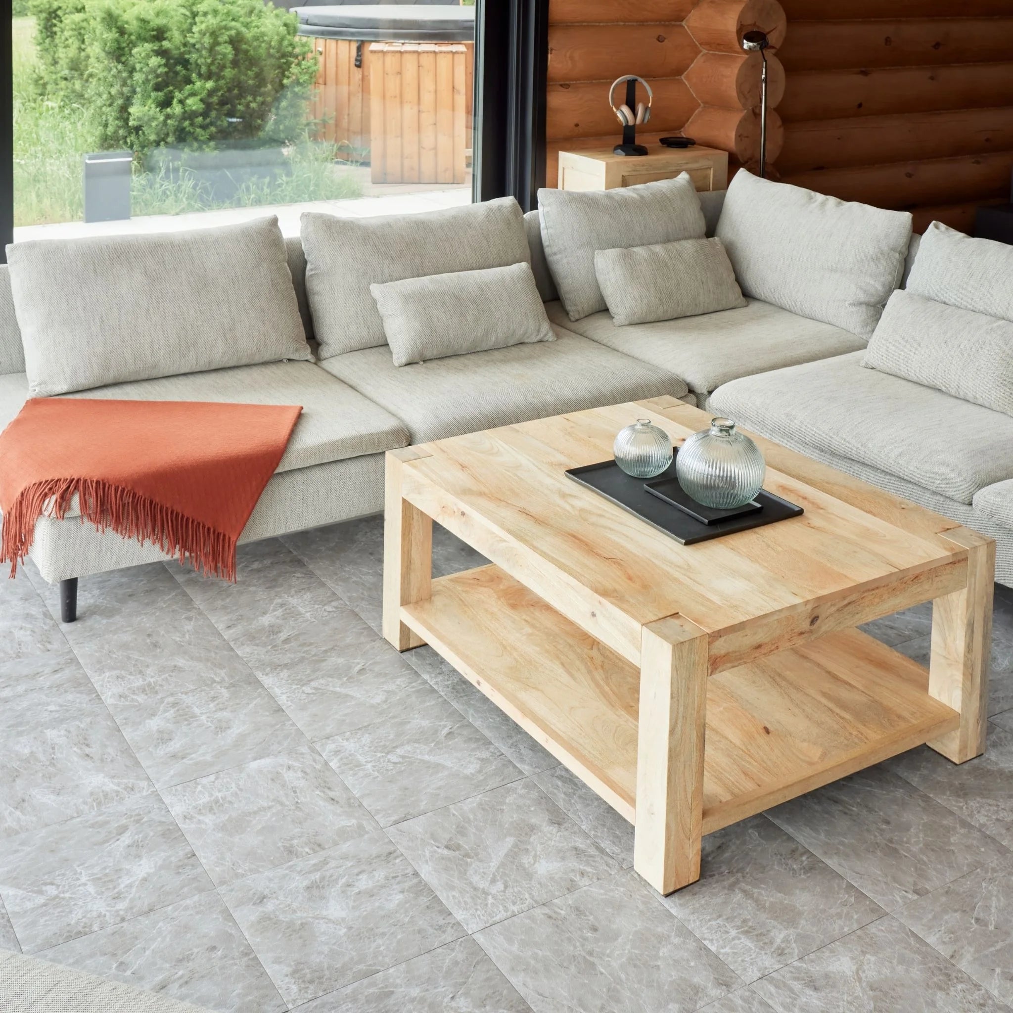 contemporary living room with large beige sofa, wooden coffee table, and light grey tile flooring