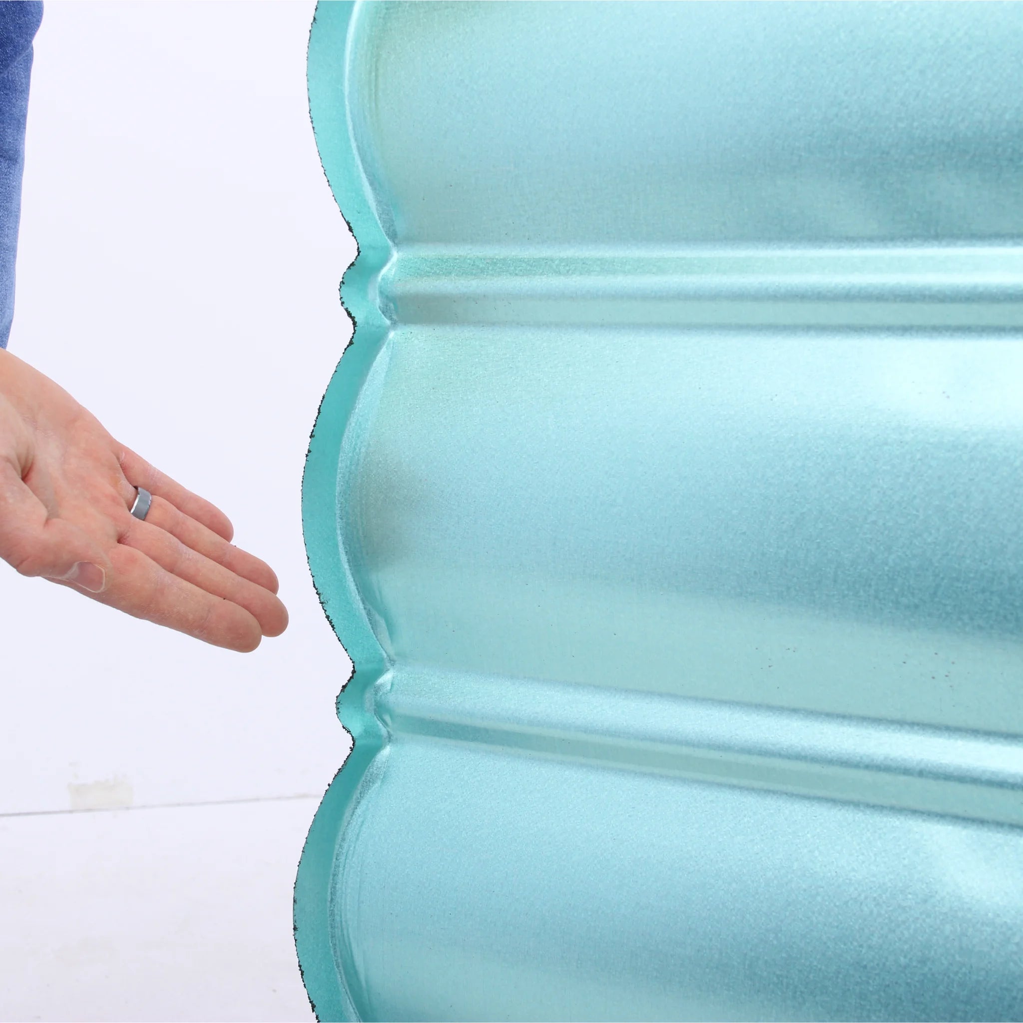 a person displays the backside of a roof shingle made of a galvanized zinc-coated metal sheet