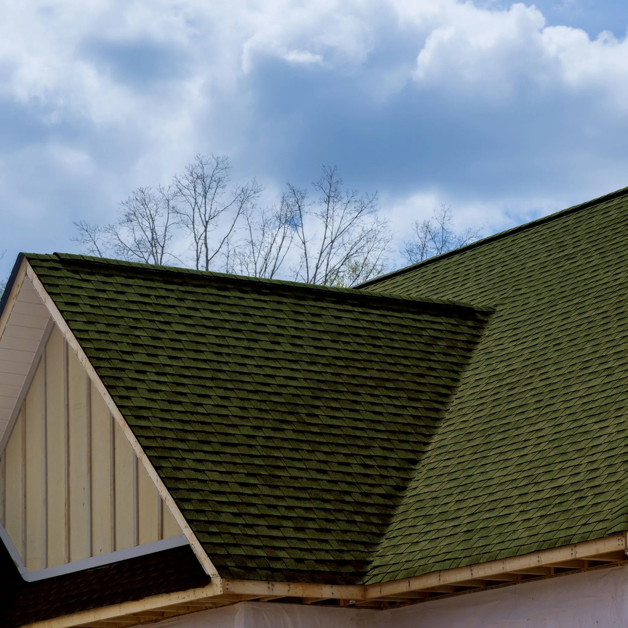 roof with installed green shingles against sky