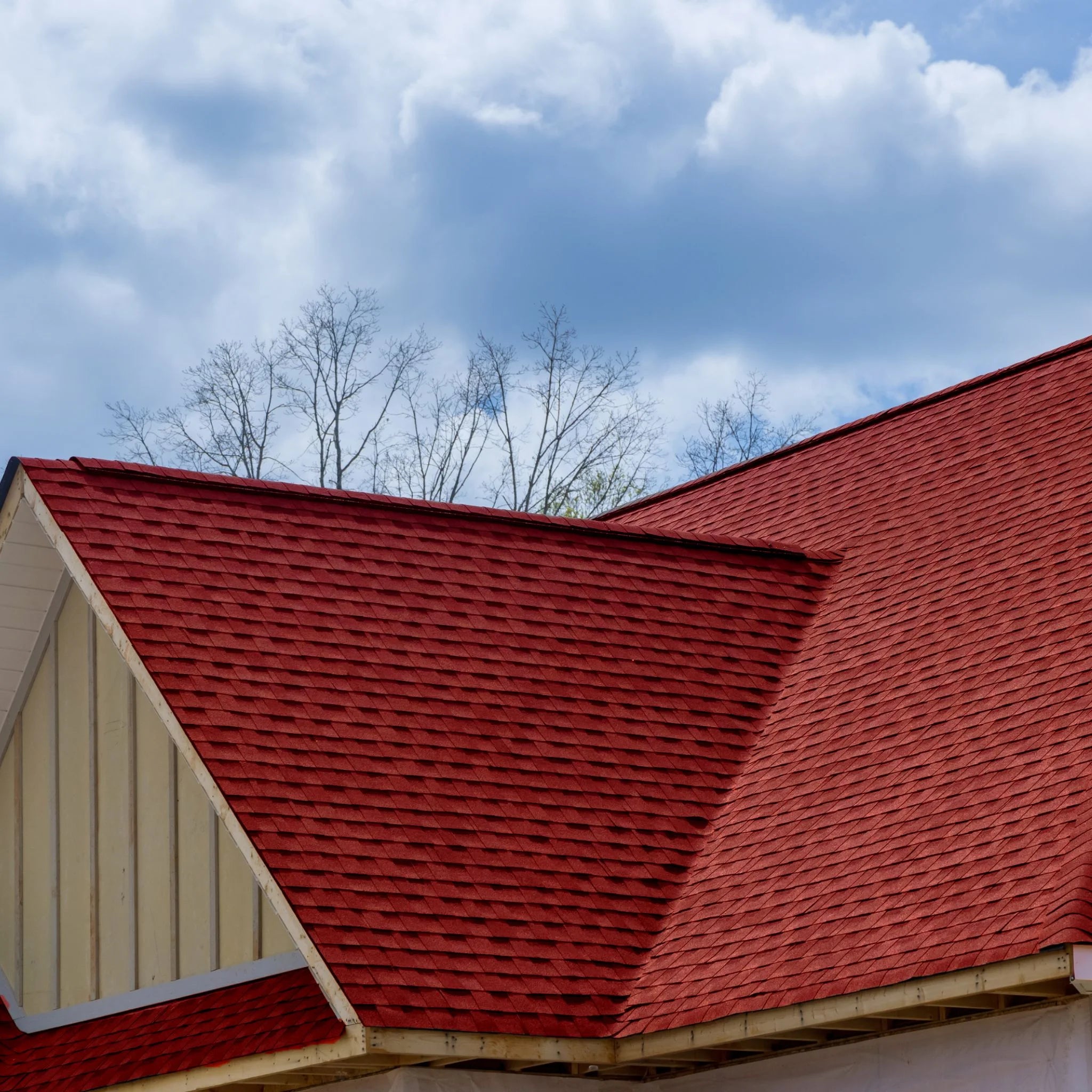 roof with installed red shingles against blue sky