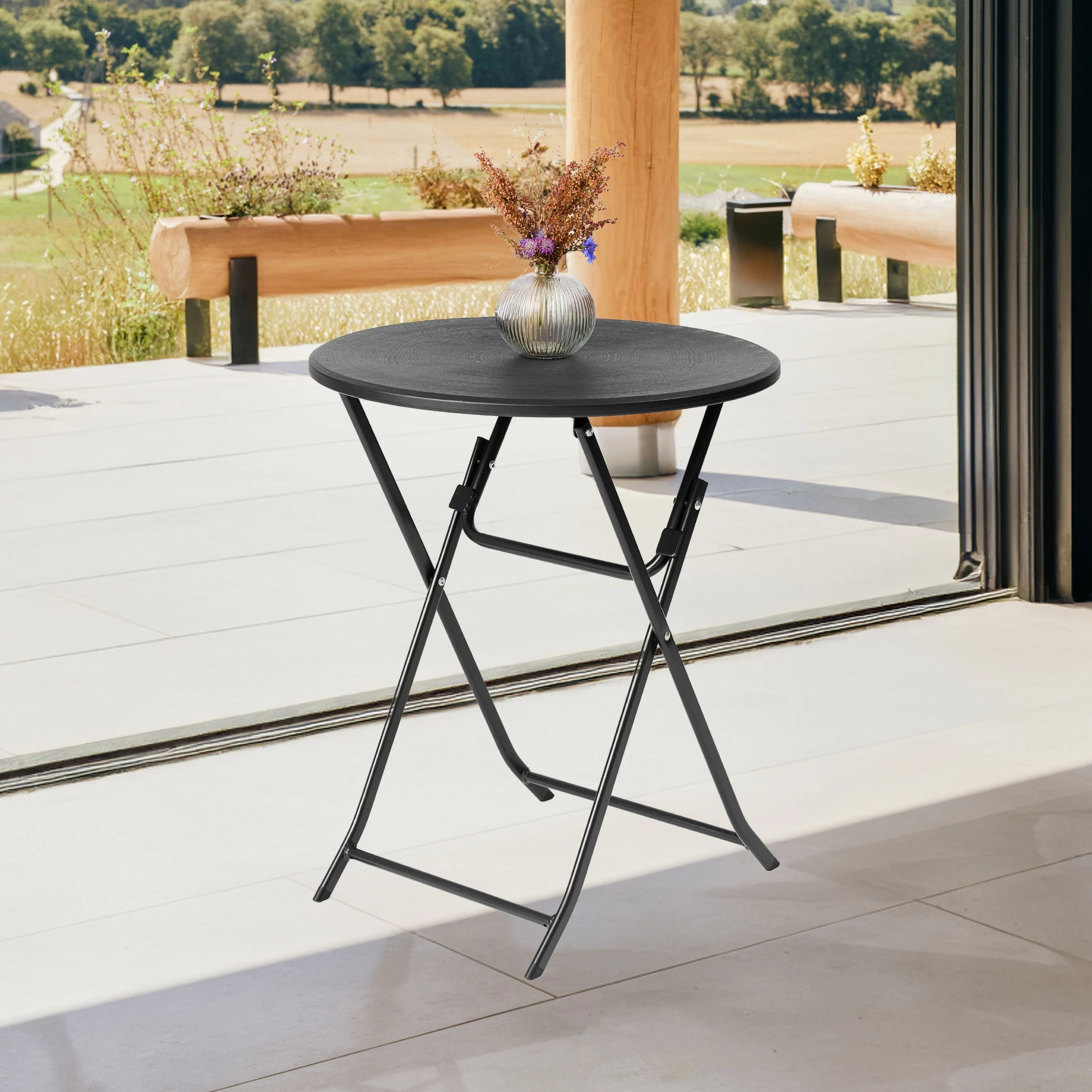 black round folding table on patio with flower vase