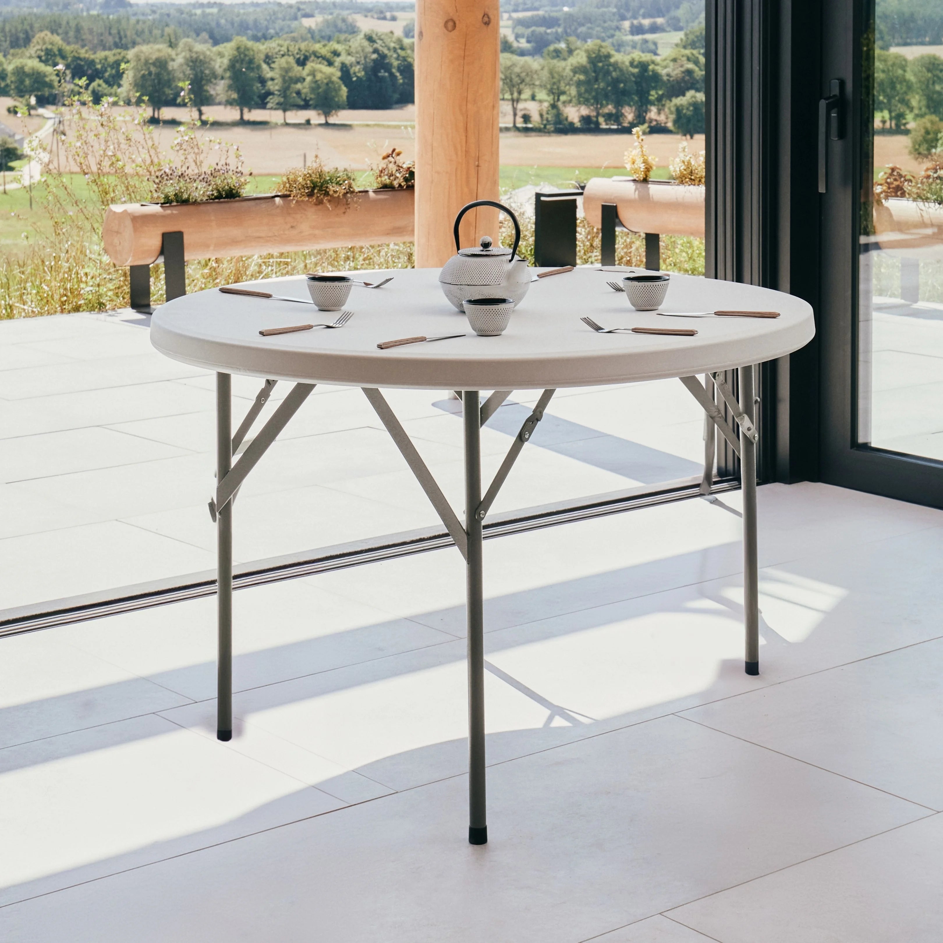 white round folding table on patio with flower vase