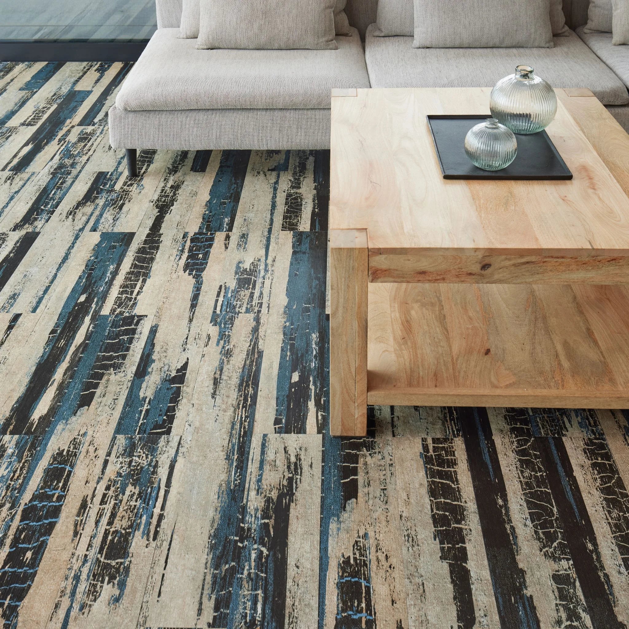 modern living room featuring grey sofa and light wood furniture on distresed light and dark flooring