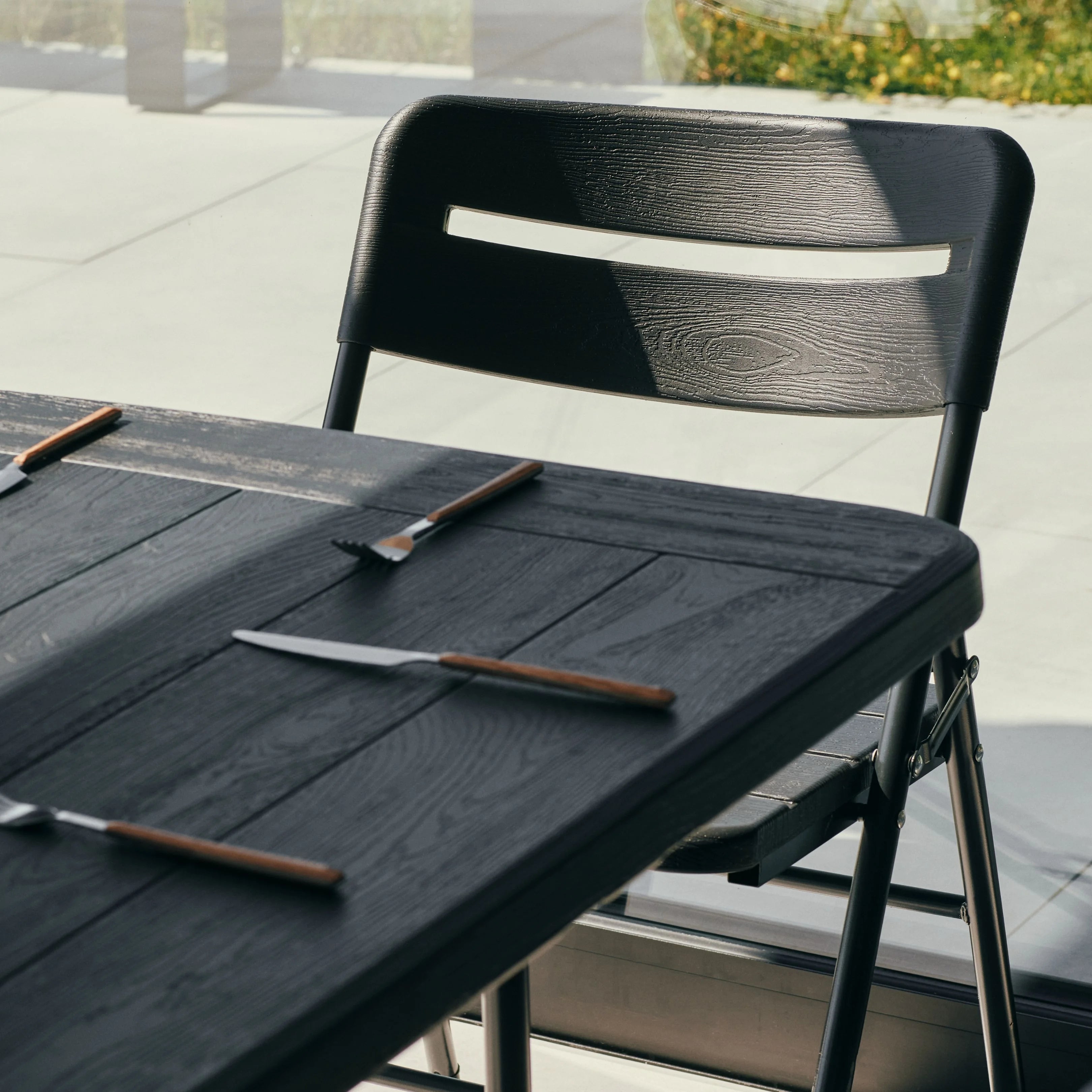 close up of black 6ft table and chair with utensils on top