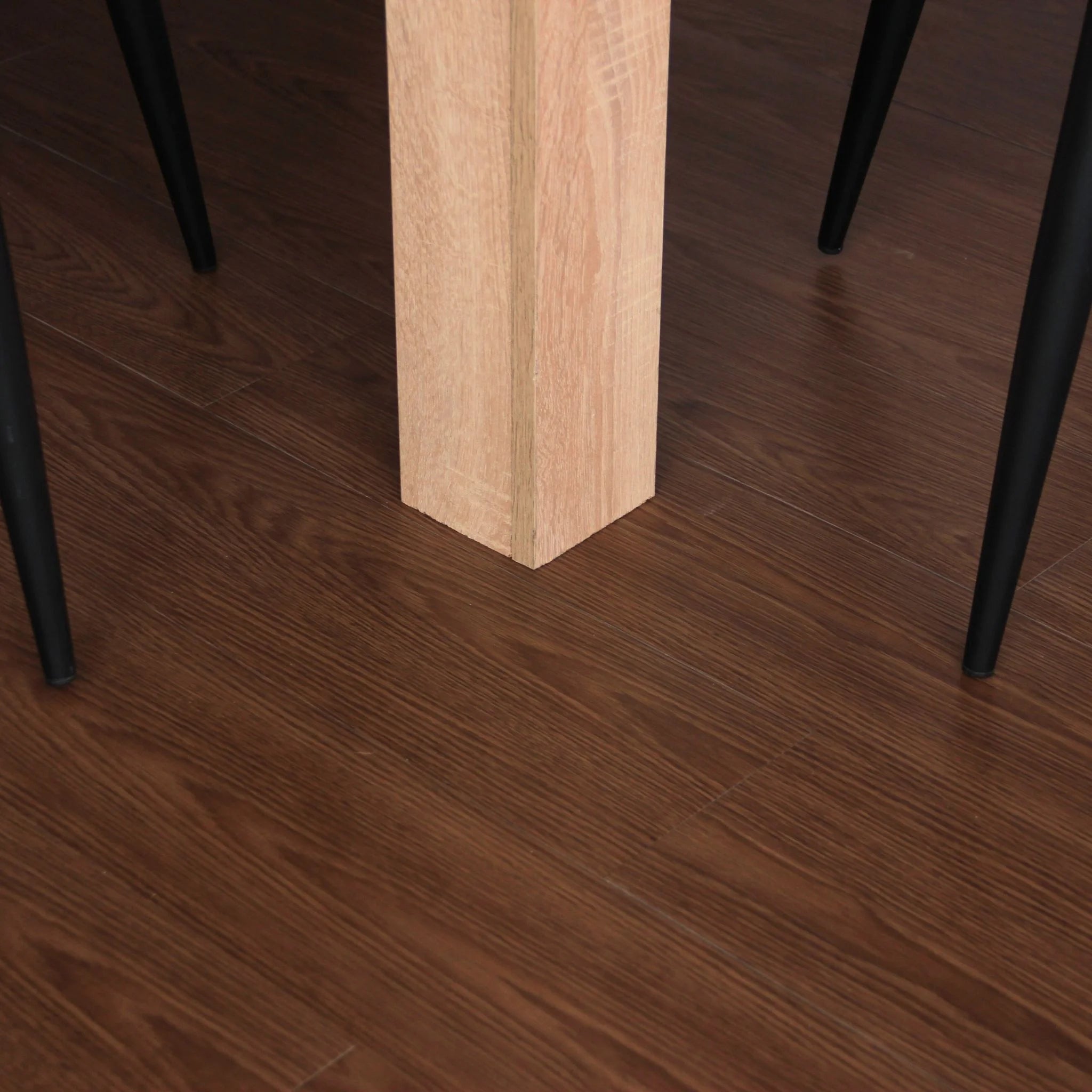 brown wood effect vinyl flooring under a table and black metal chairs
