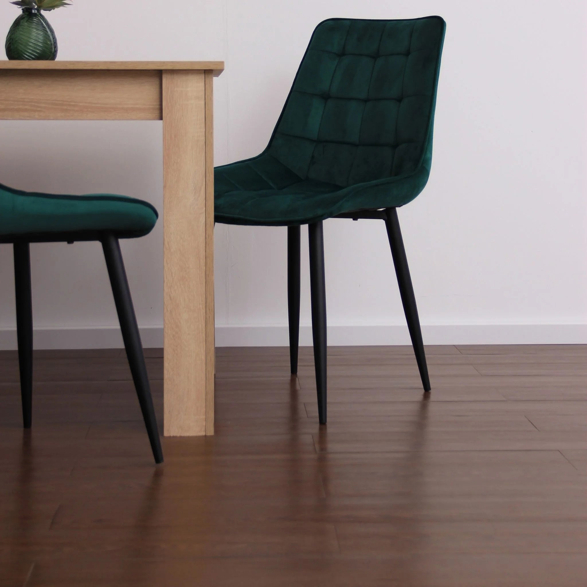 contemporary dining room featuring green velvet chairs and light wood furniture on brown flooring