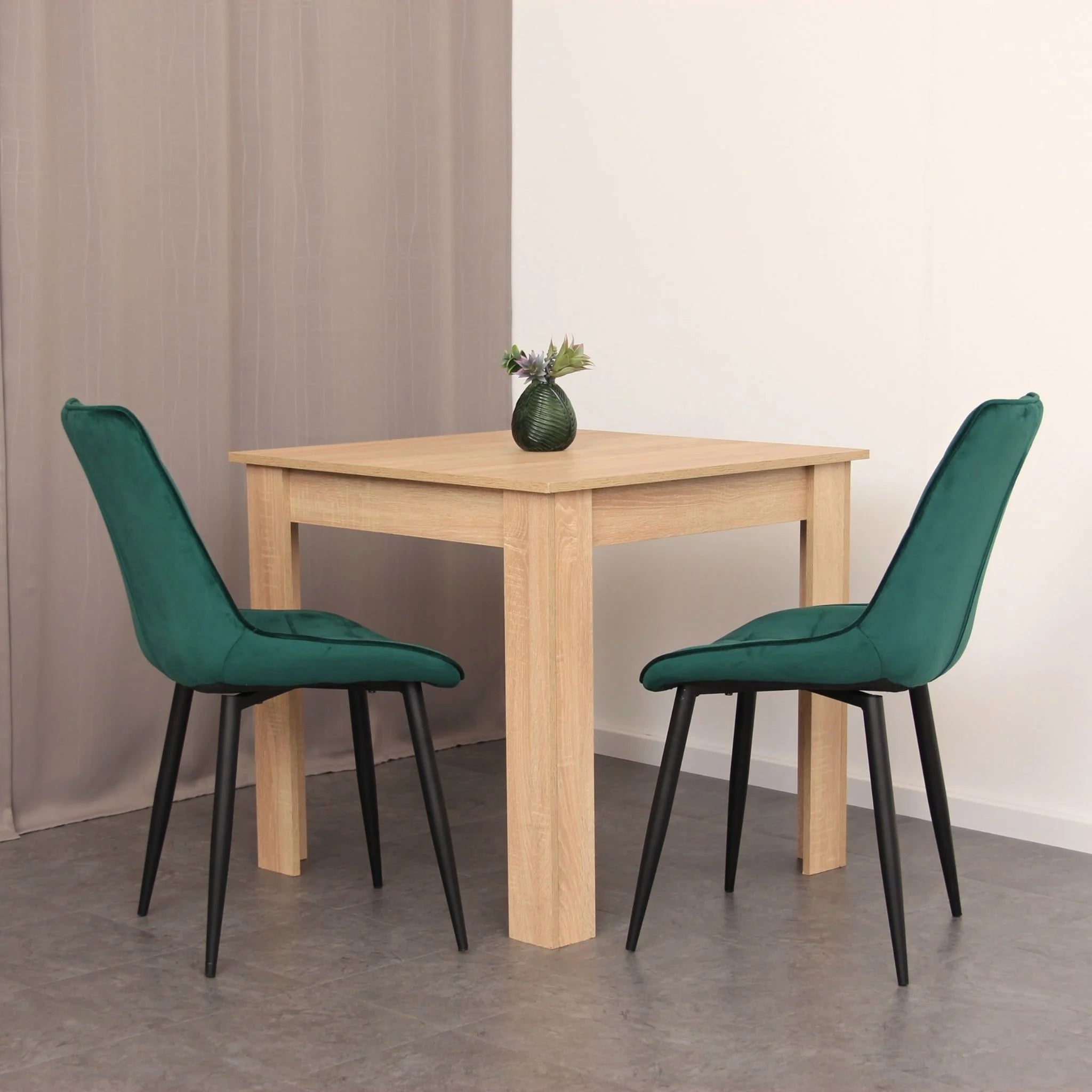 minimalist dining setup featuring green velvet chairs on dark grey tile effect flooring