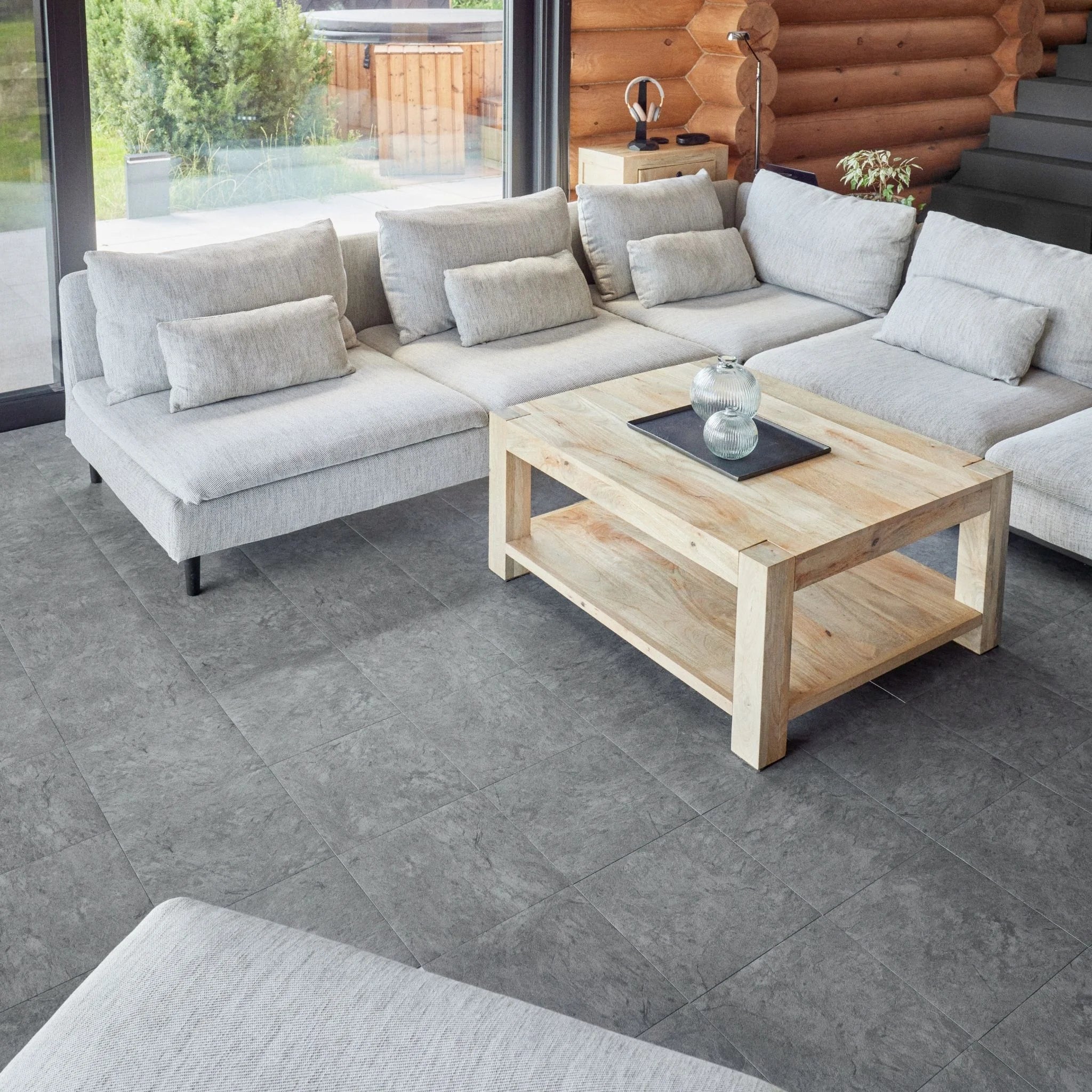 contemporary living room with large beige sofa, wooden coffee table, and grey tile flooring