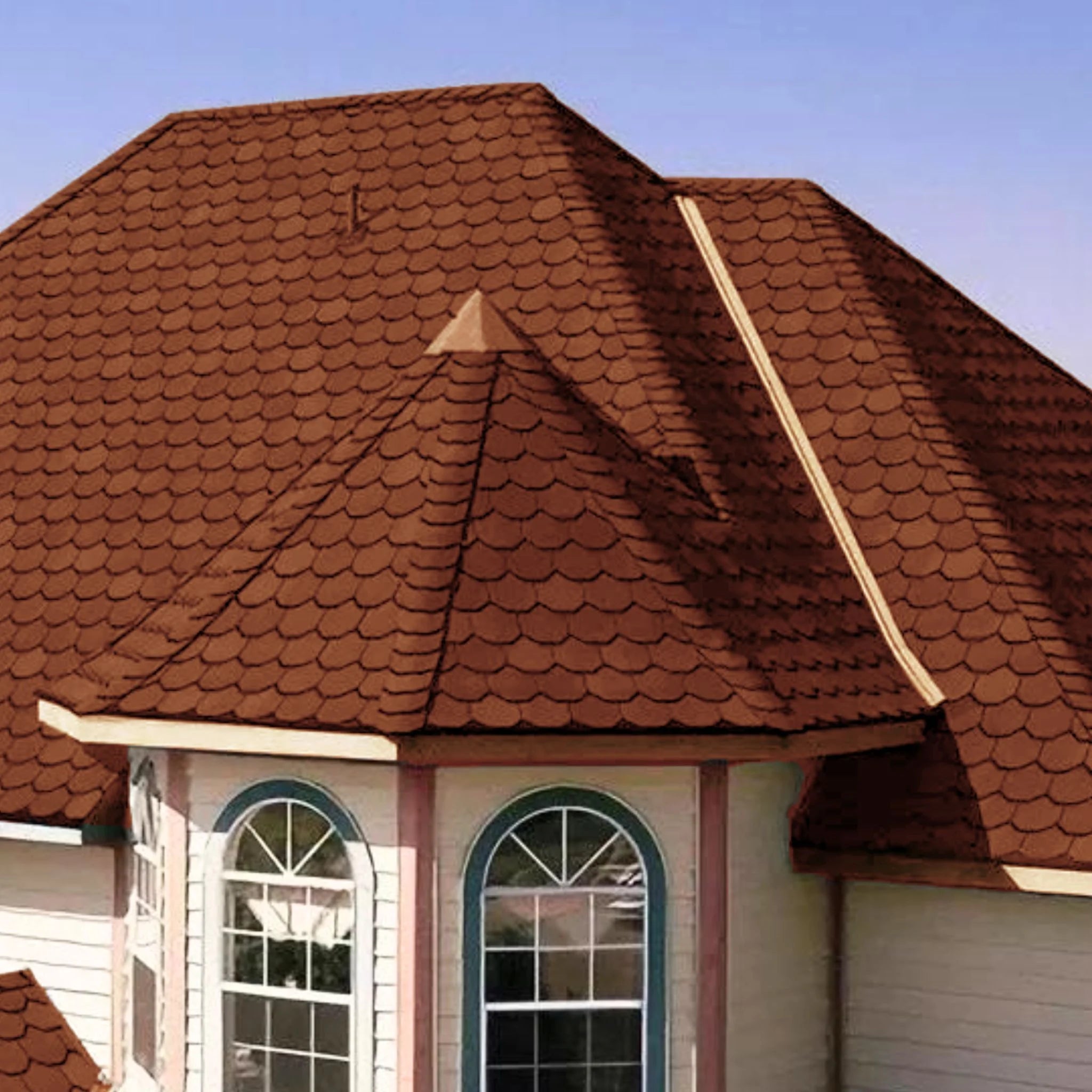 brick house with brown shingle roof under blue sky