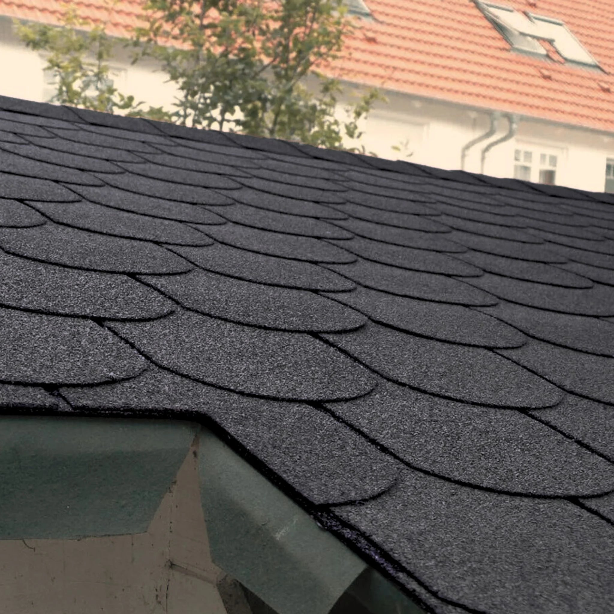 roof with installed graphite fish scales shape shingles against blue sky