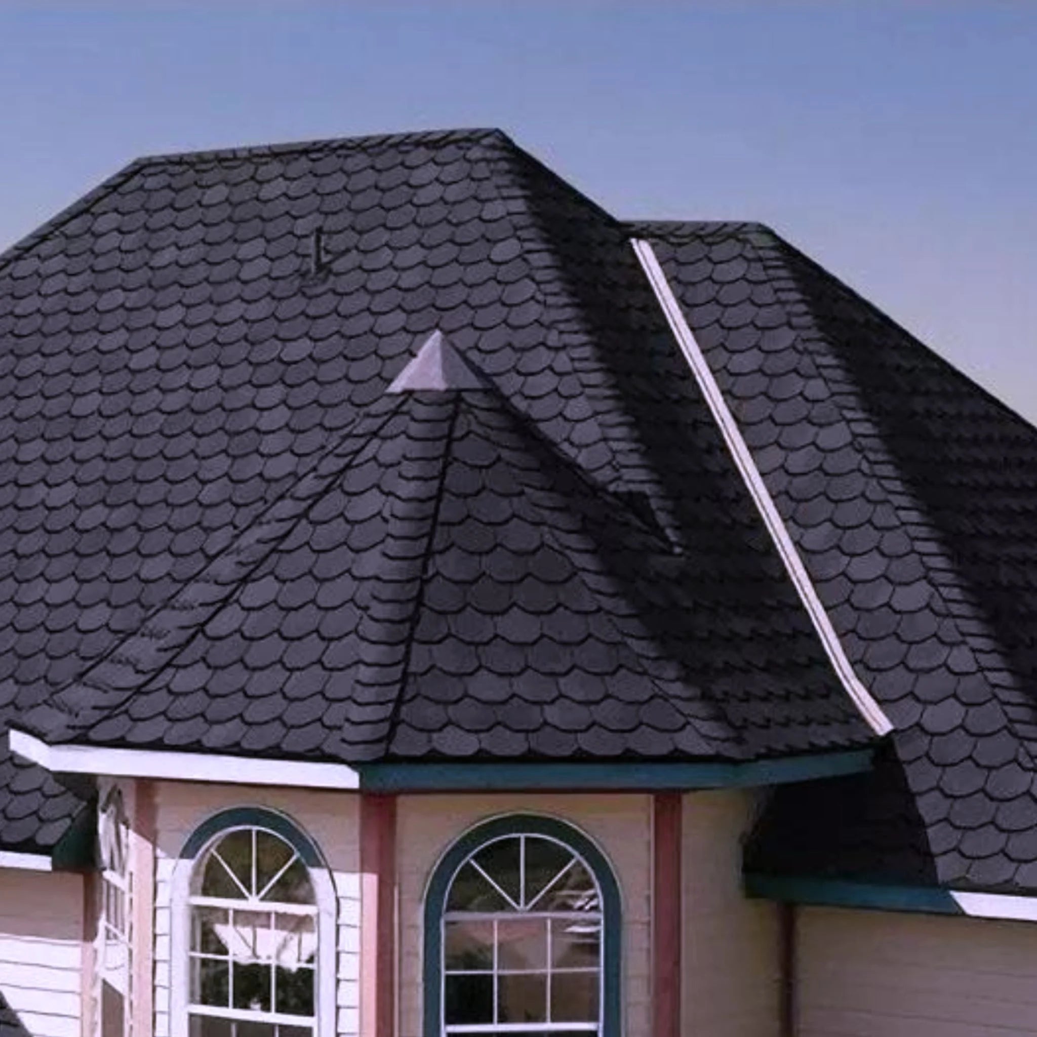 brick house with graphite shingle roof under blue sky