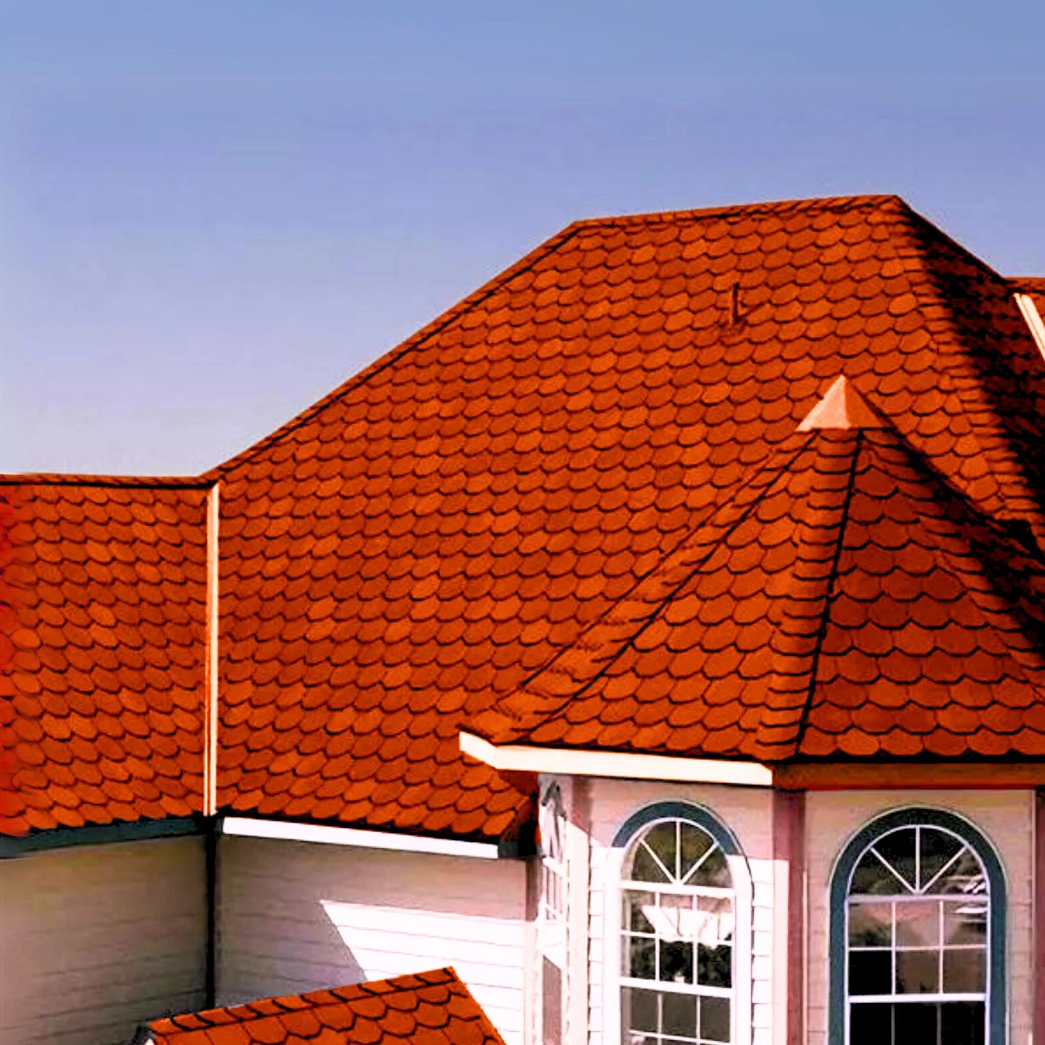 brick house with red shingle roof under blue sky