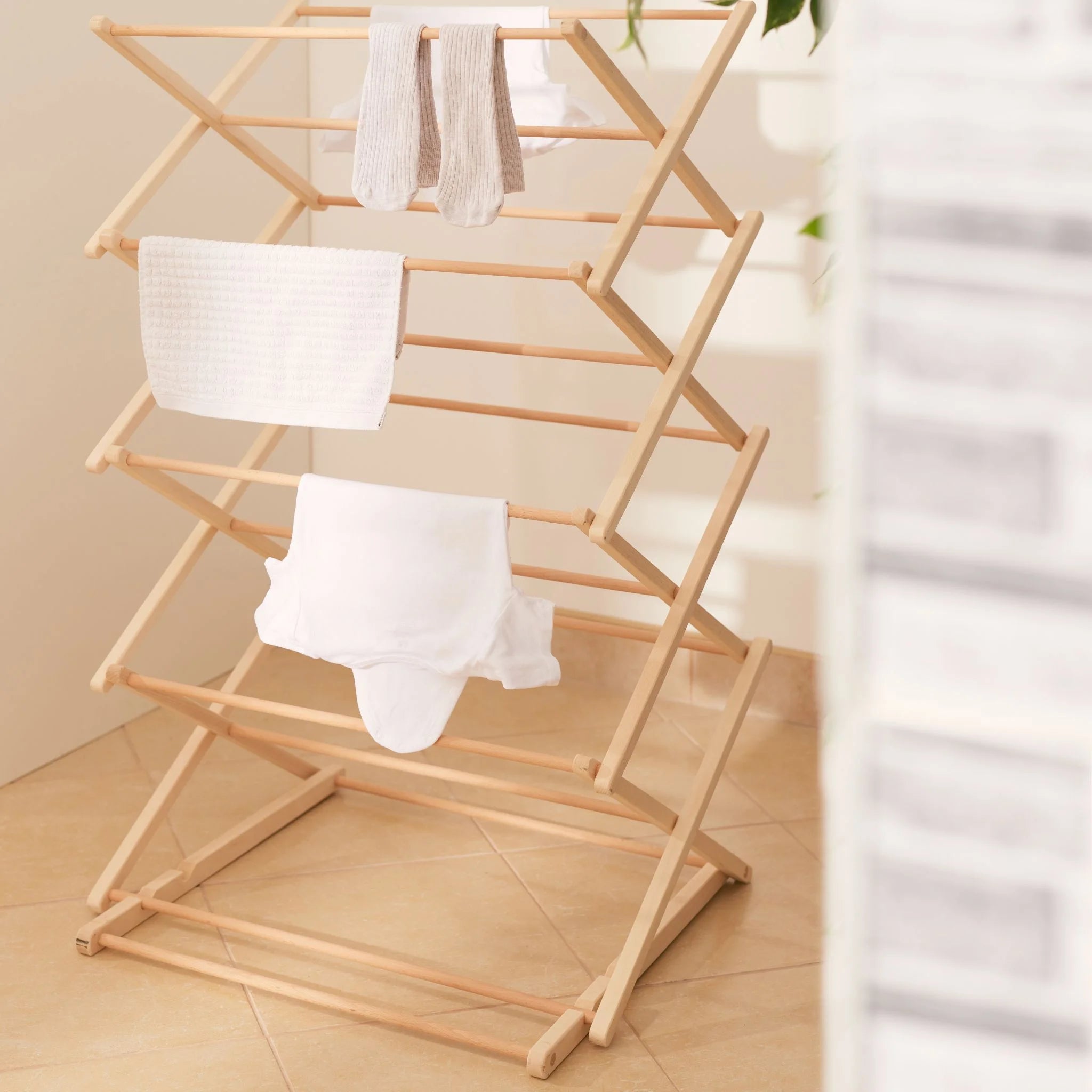 Wooden laundry drying rack with clothes in a room