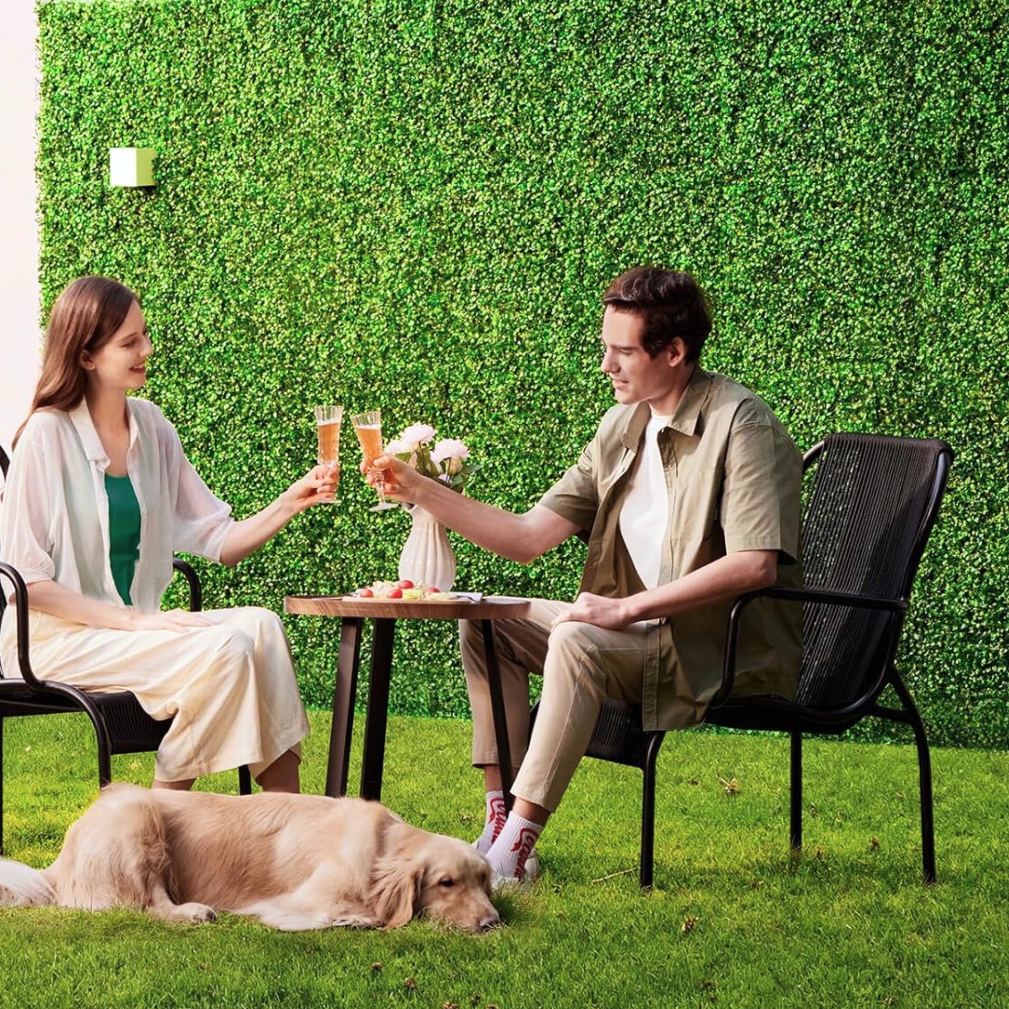 Couple enjoying drinks in garden with lush green wall panel