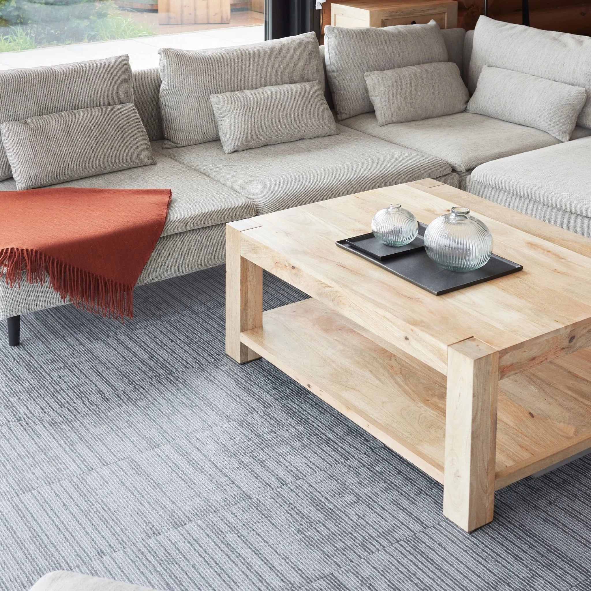 living room with grey textured carpet, beige sofa, and wooden coffee table