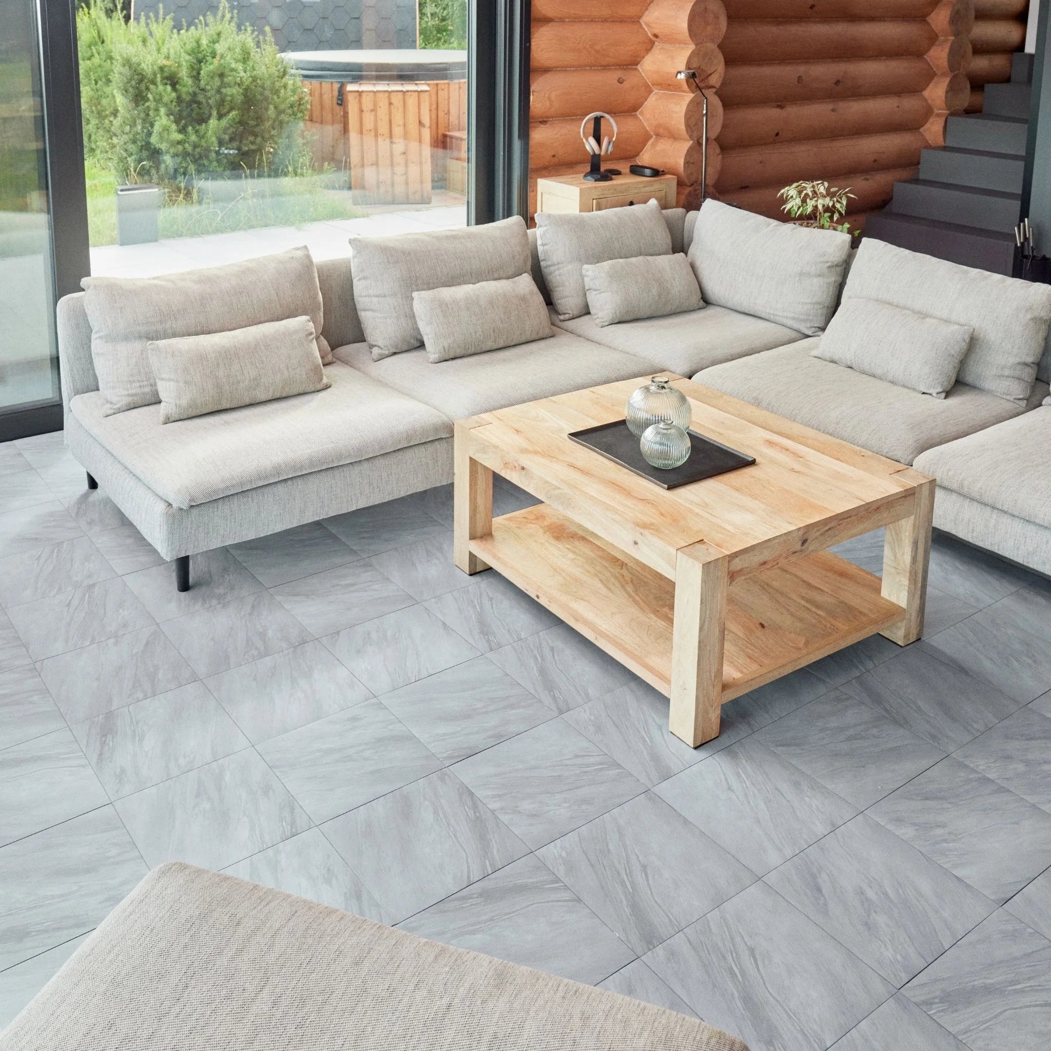 contemporary living room with large beige sofa, wooden coffee table, and grey tile flooring