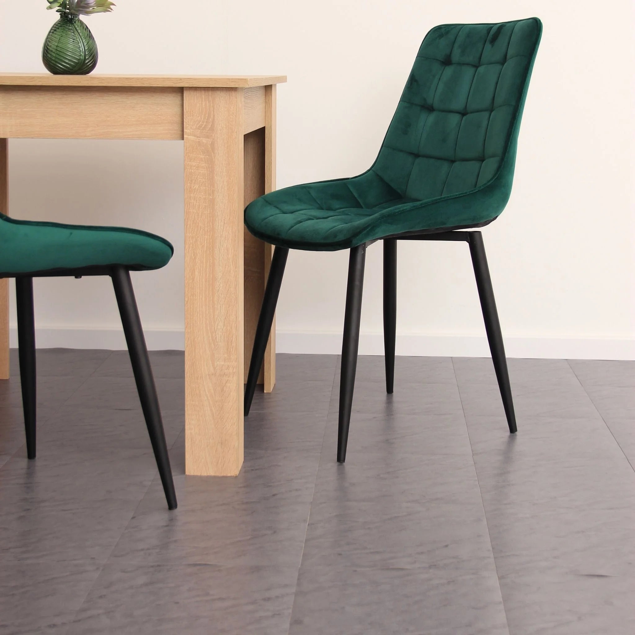 contemporary dining room featuring green velvet chairs and light wood furniture on grey flooring