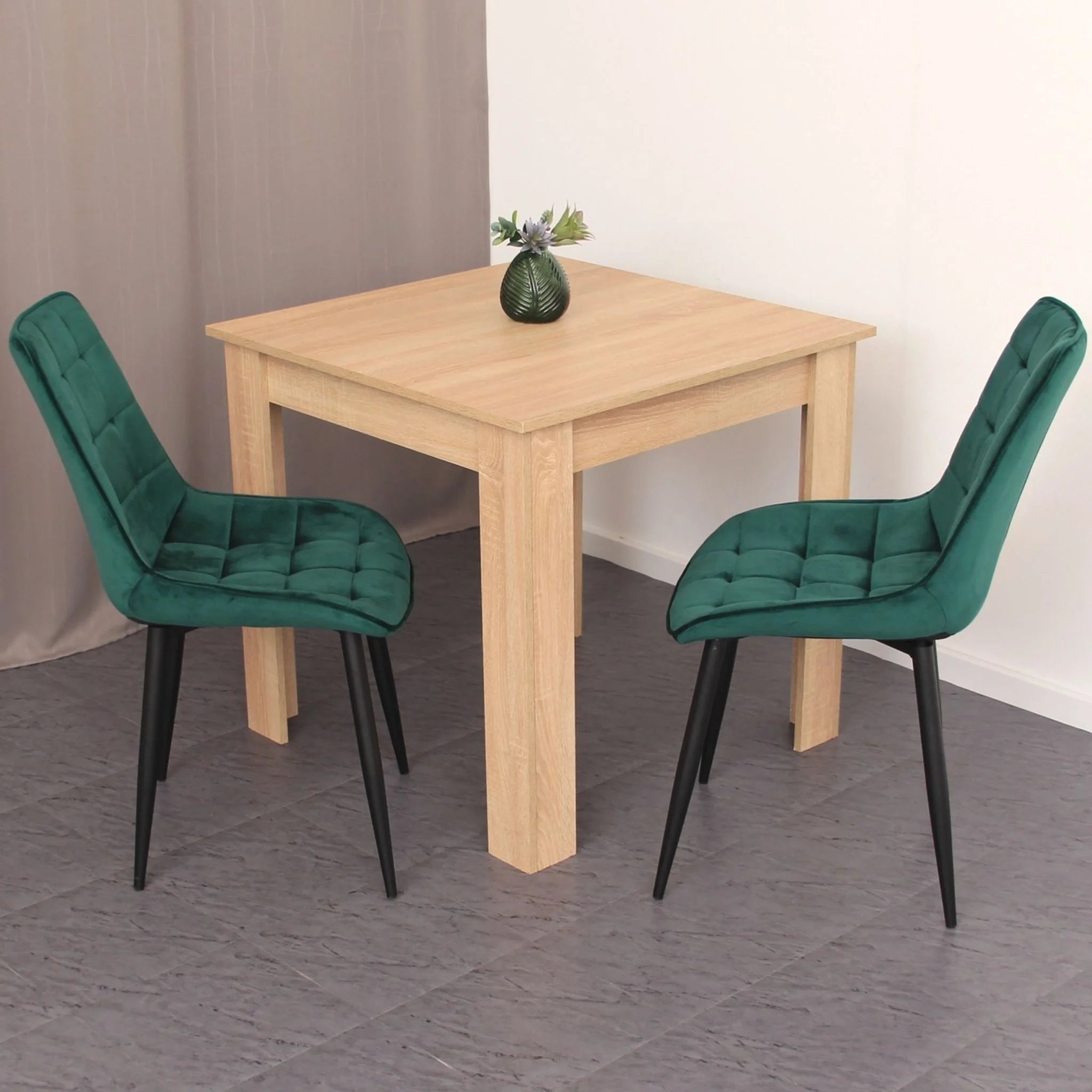 minimalist dining setup featuring green velvet chairs on grey tile effect flooring