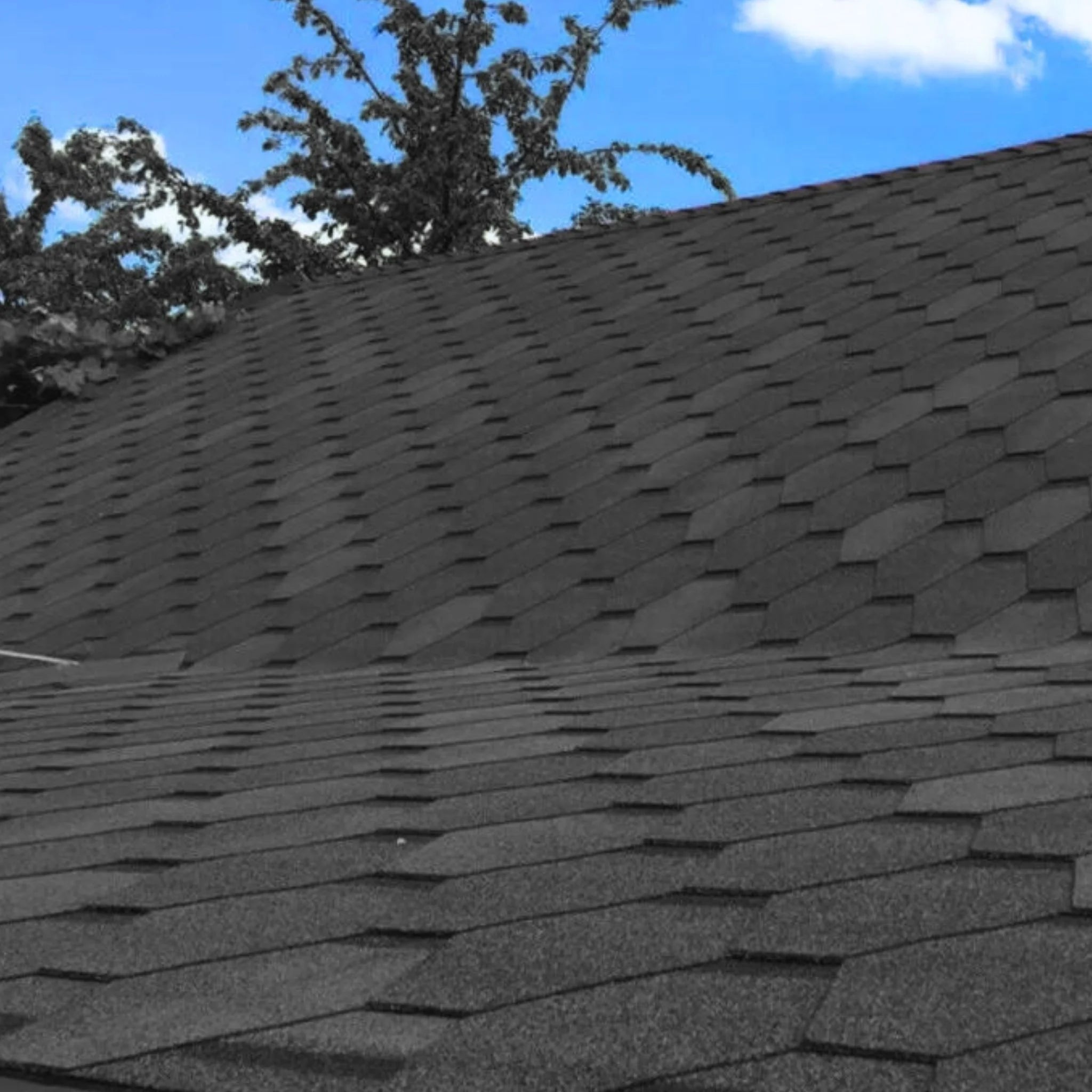 roof with installed graphite hexagonal shingles against blue sky