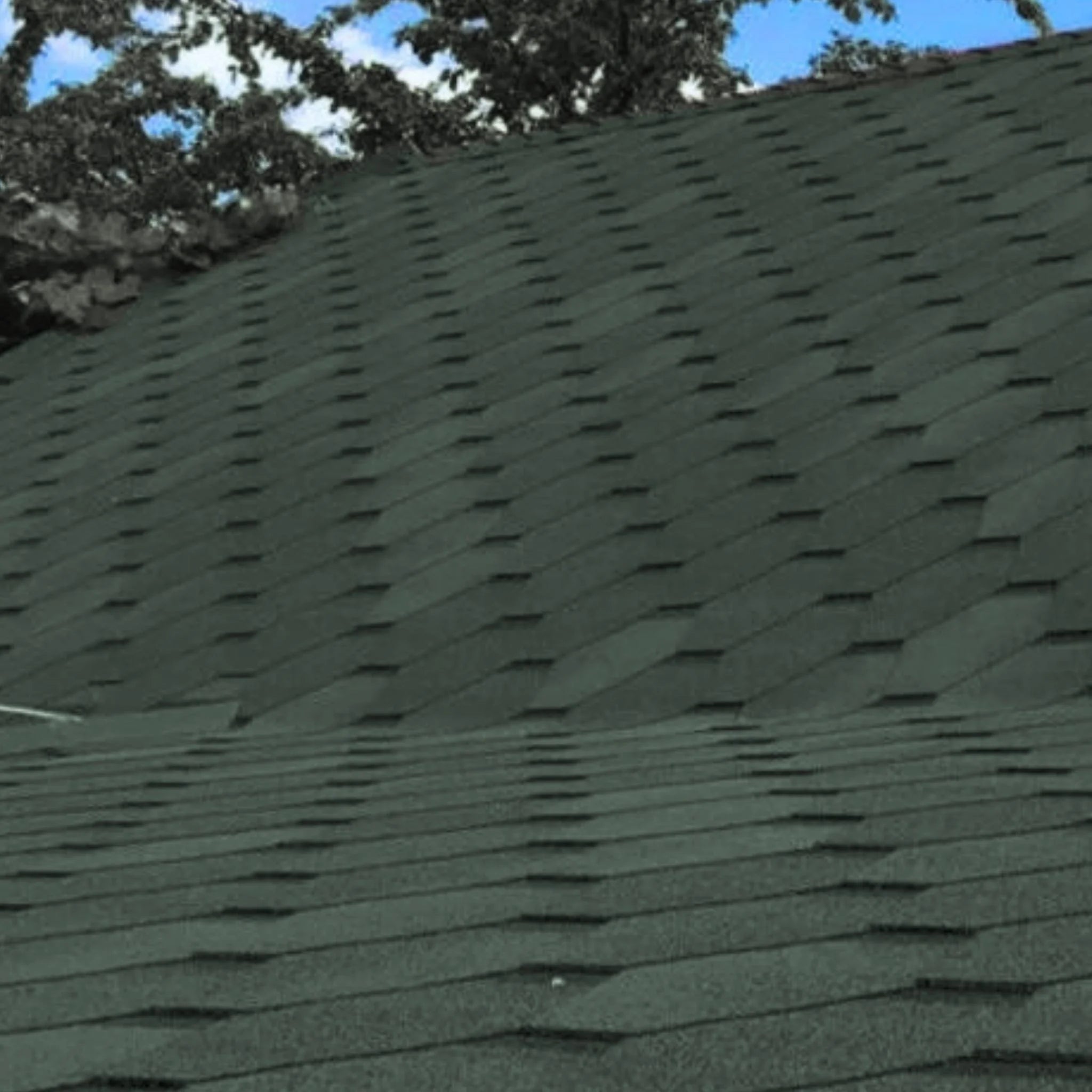 roof with installed green hexagonal shingles against blue sky