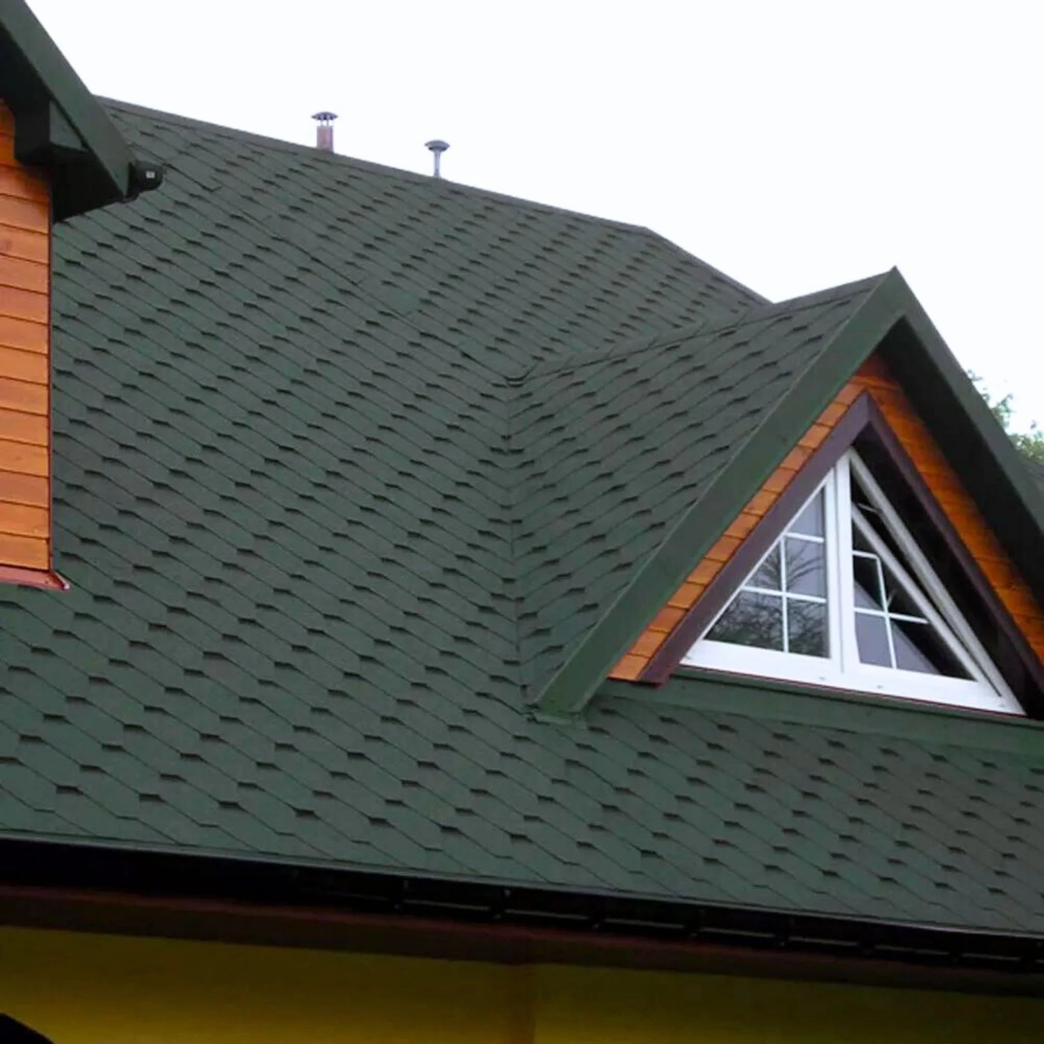 brick house with green shingle roof under blue sky