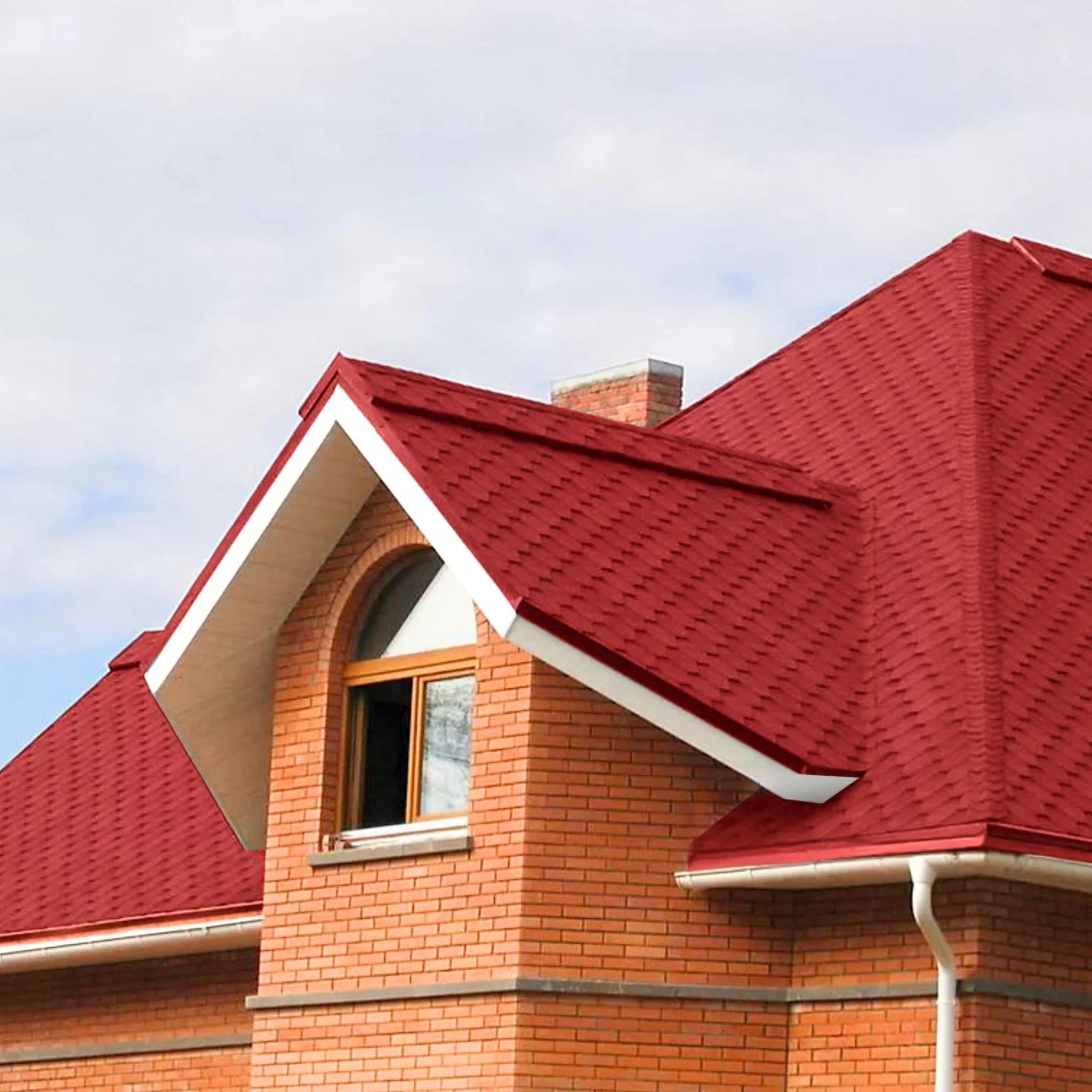 brick house with red shingle roof under blue sky