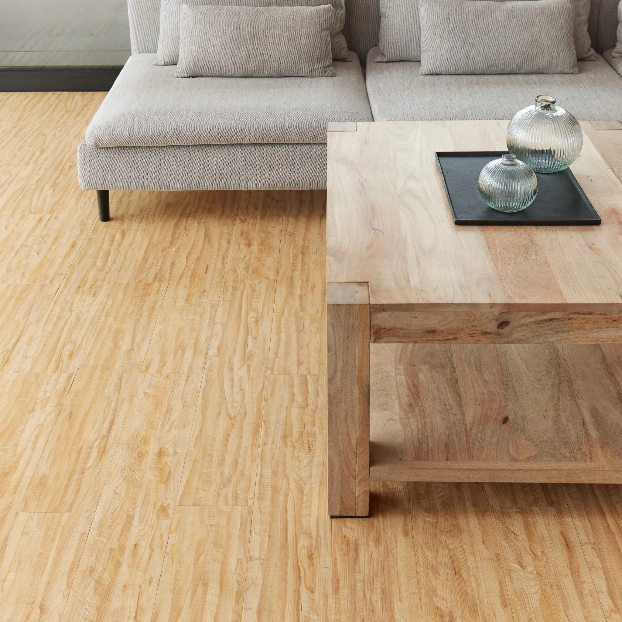 modern living room featuring grey sofa and light wood furniture on honey beige flooring