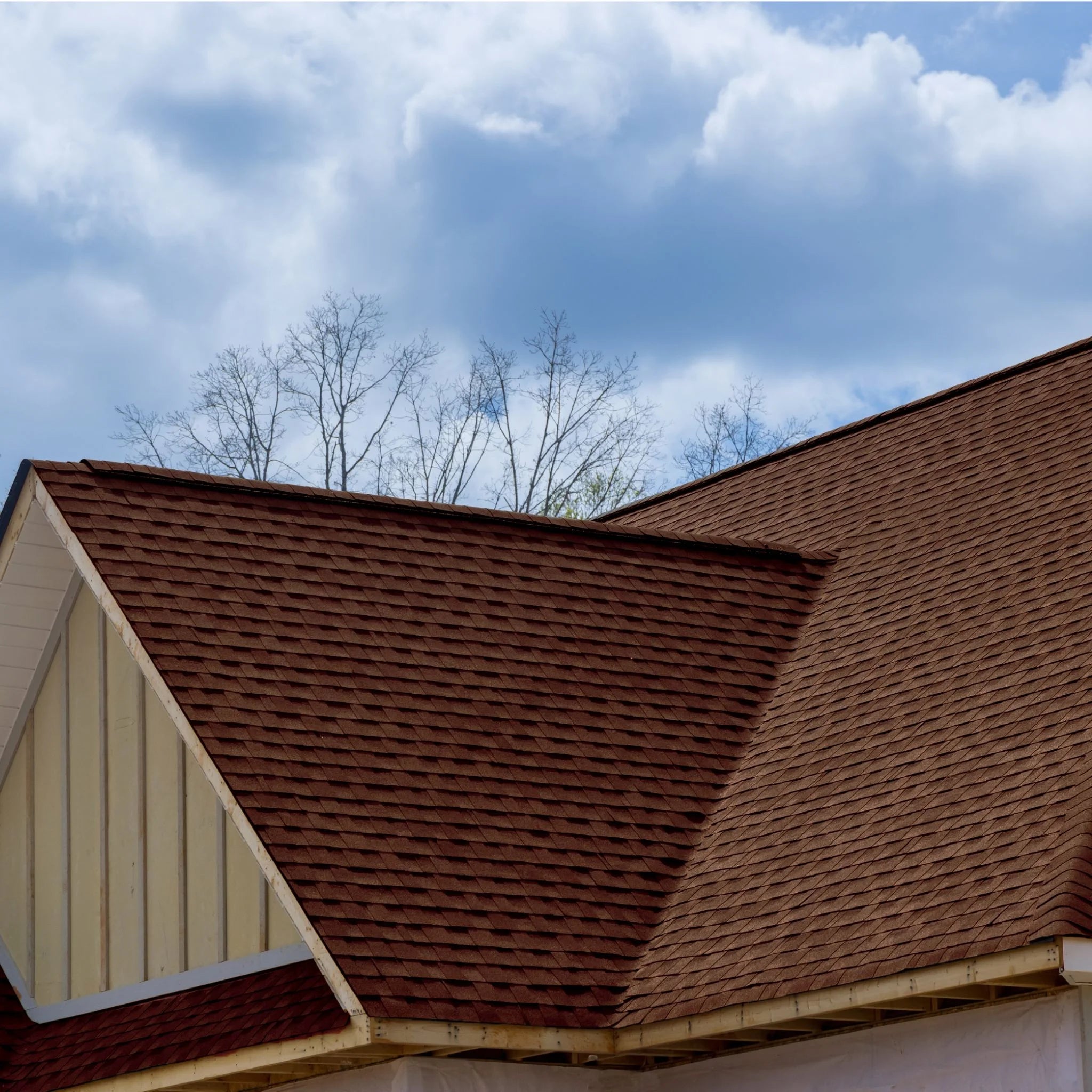 roof with installed brown shingles against sky