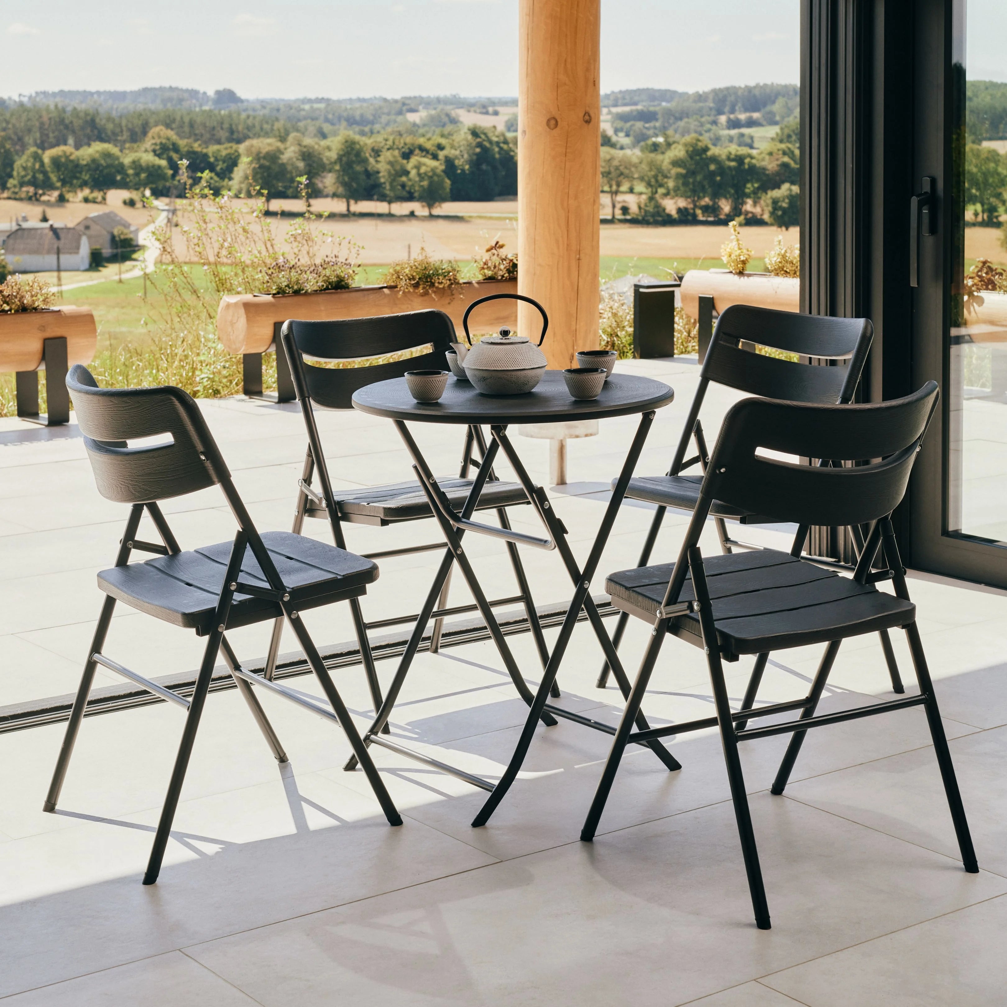 black round folding table and chair on patio with flower vase