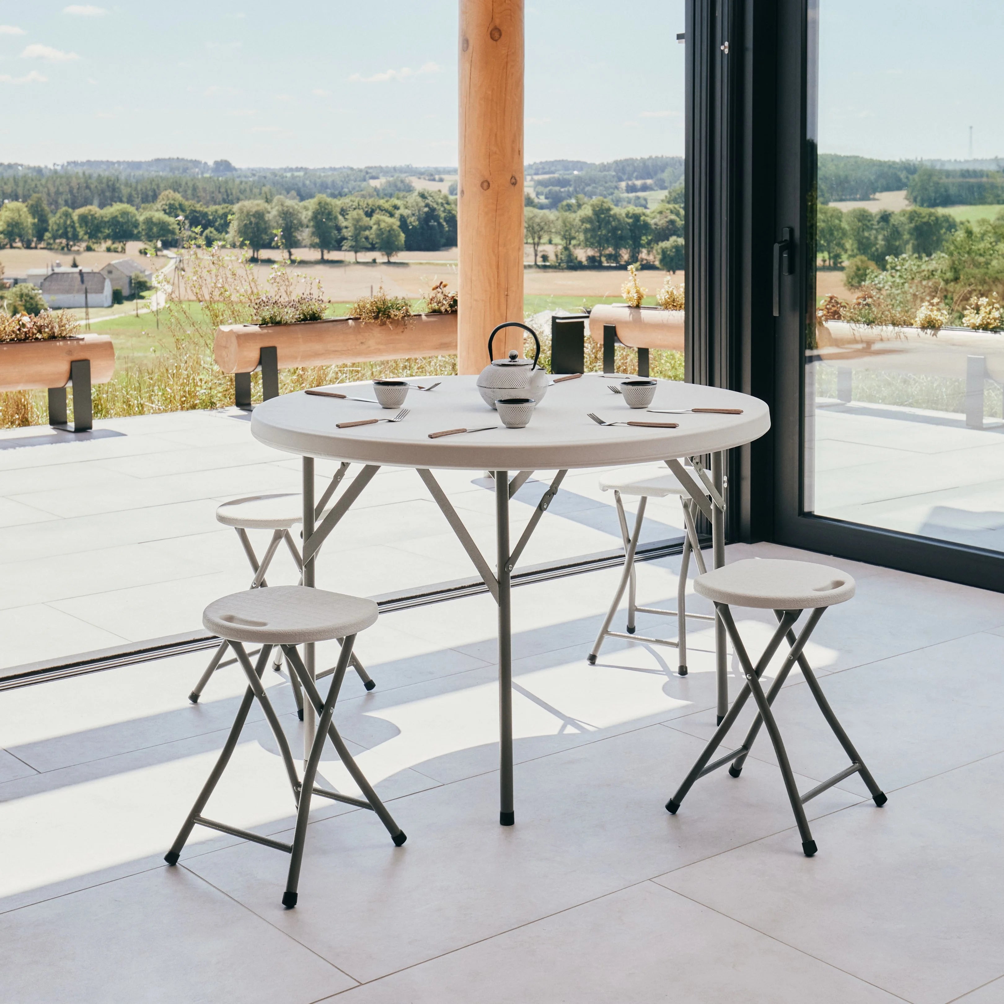 white round folding table and stool on patio with a scenic view